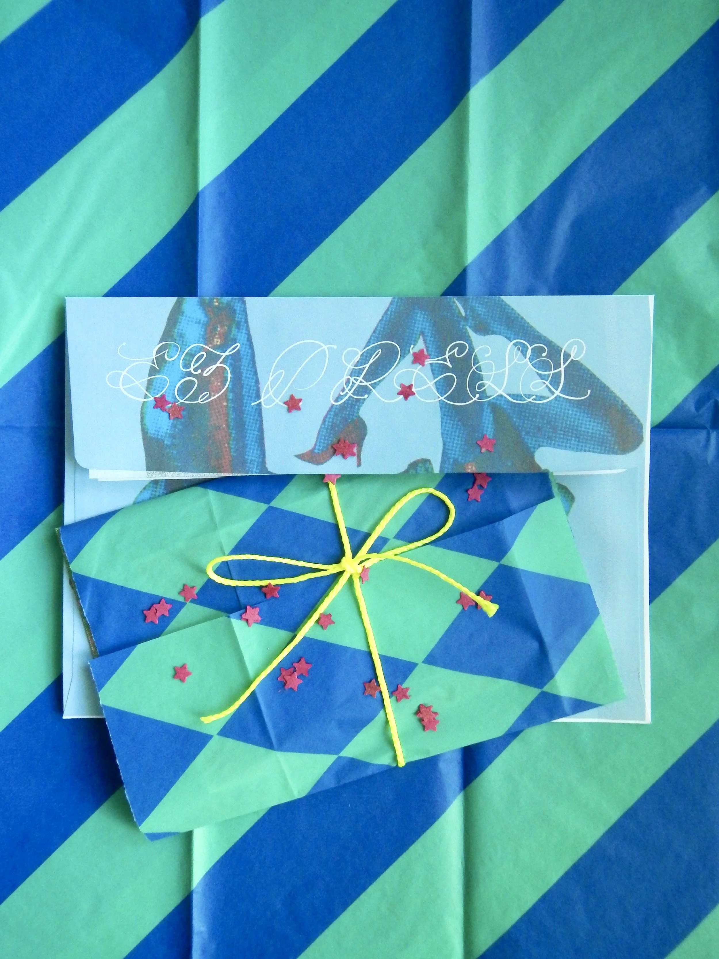 May's print club edition, an envelope the reads EZ Press, green and blue tissue paper, yellow string, and star confetti. Click this photo to go to the Print club page