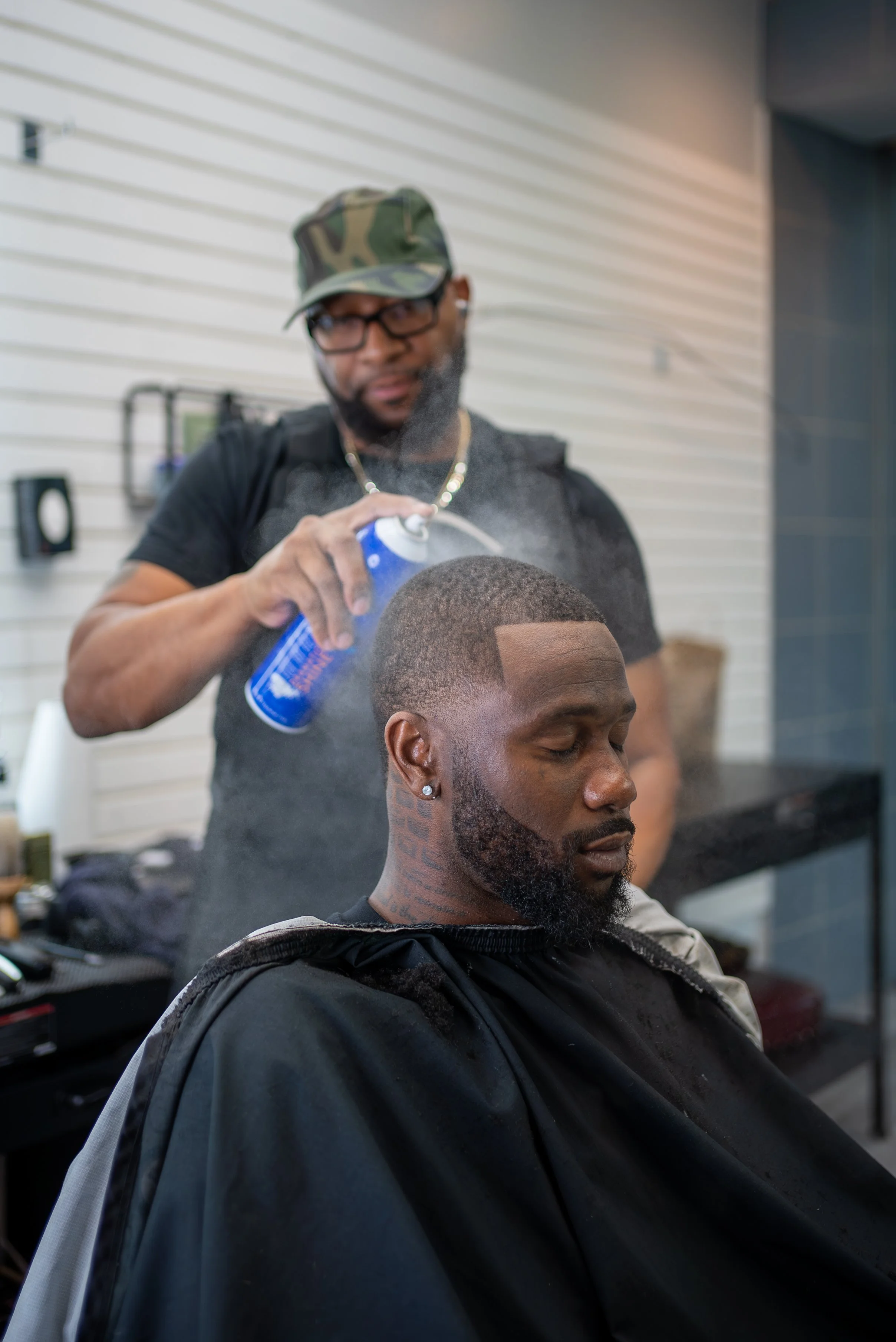 man spraying hairspray in a barber shop