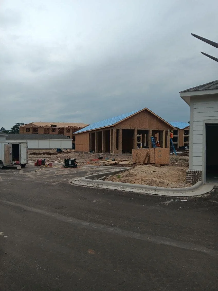 New residential construction site with unfinished houses, construction materials, and tools scattered on the ground.