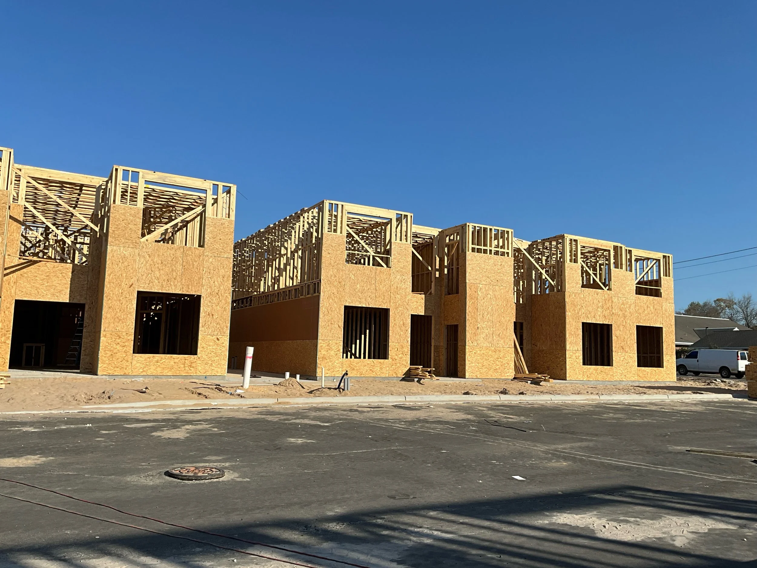 Construction site with partially built wooden structures against a clear blue sky.