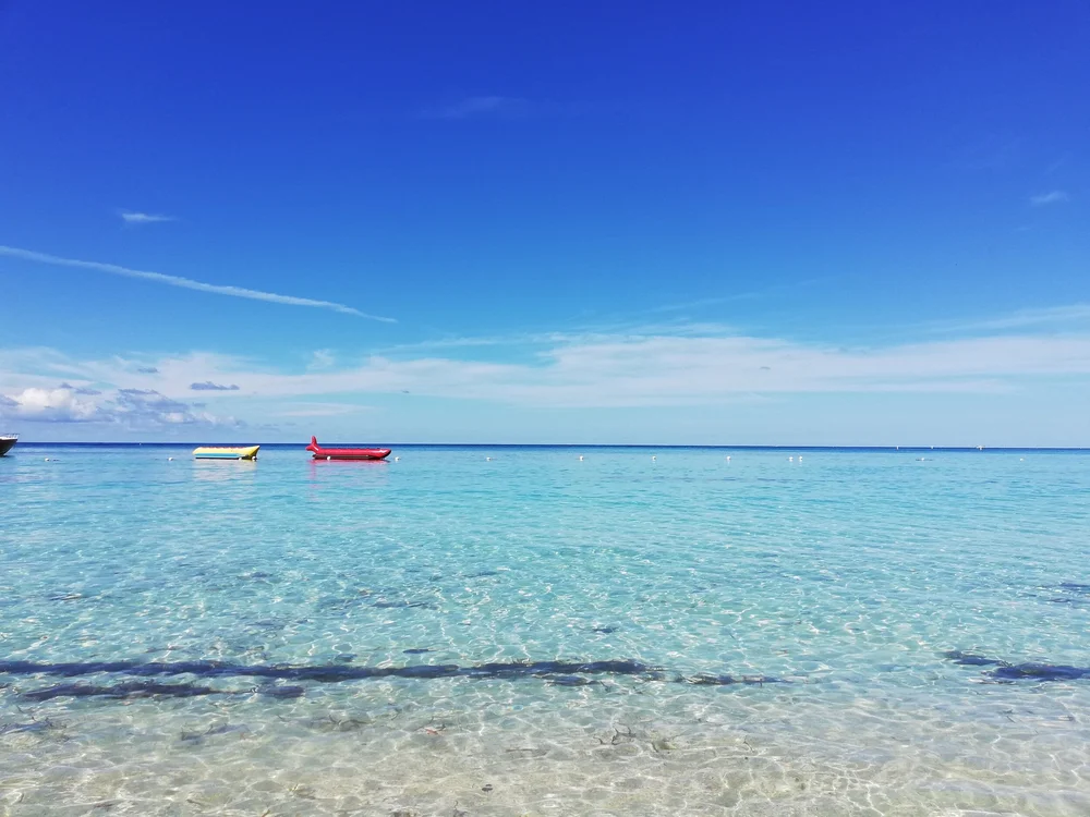 Turquoise water with colorful boats under a bright sky