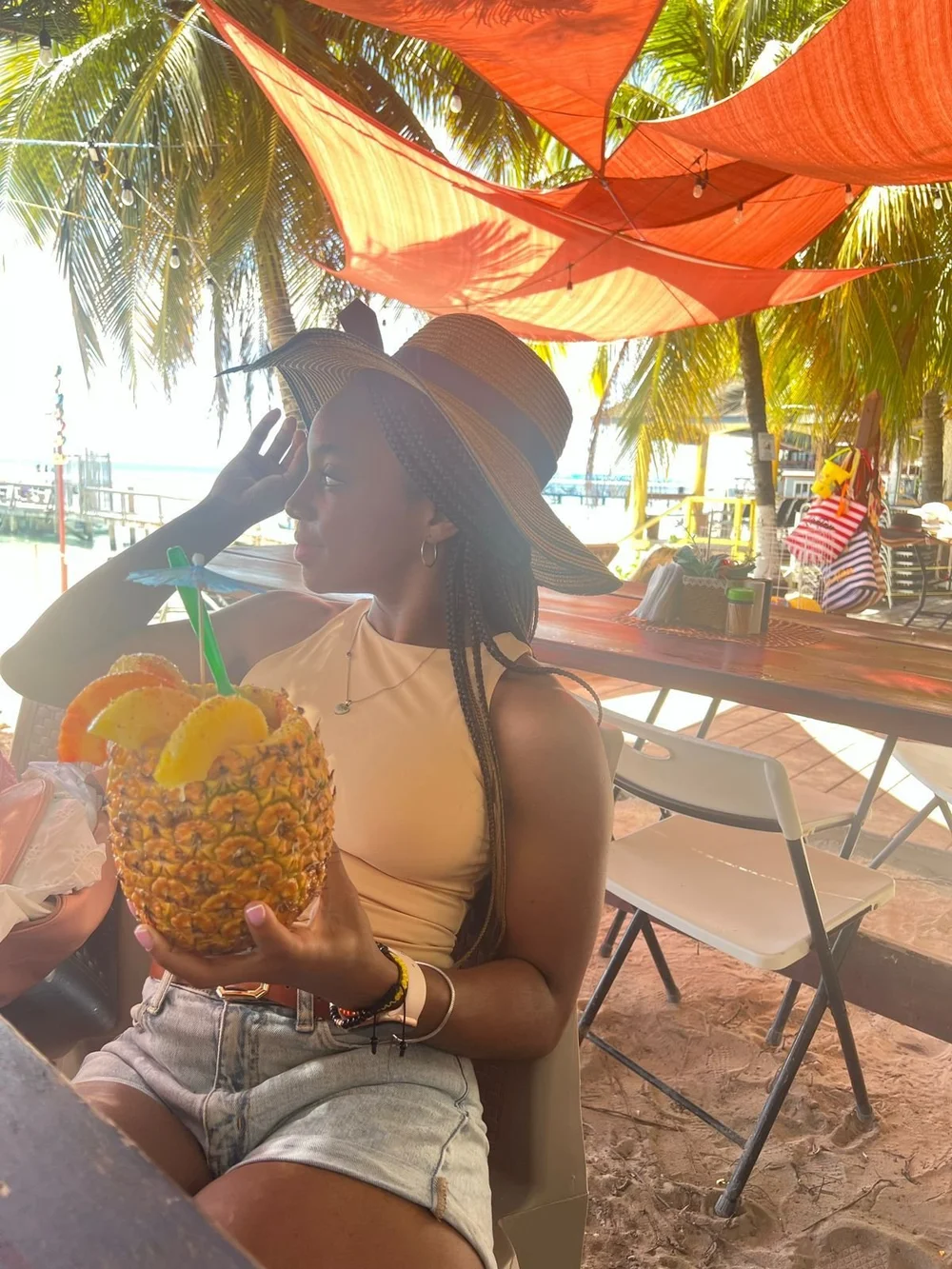 Roxana at a beachside cafe holding a pineapple drink