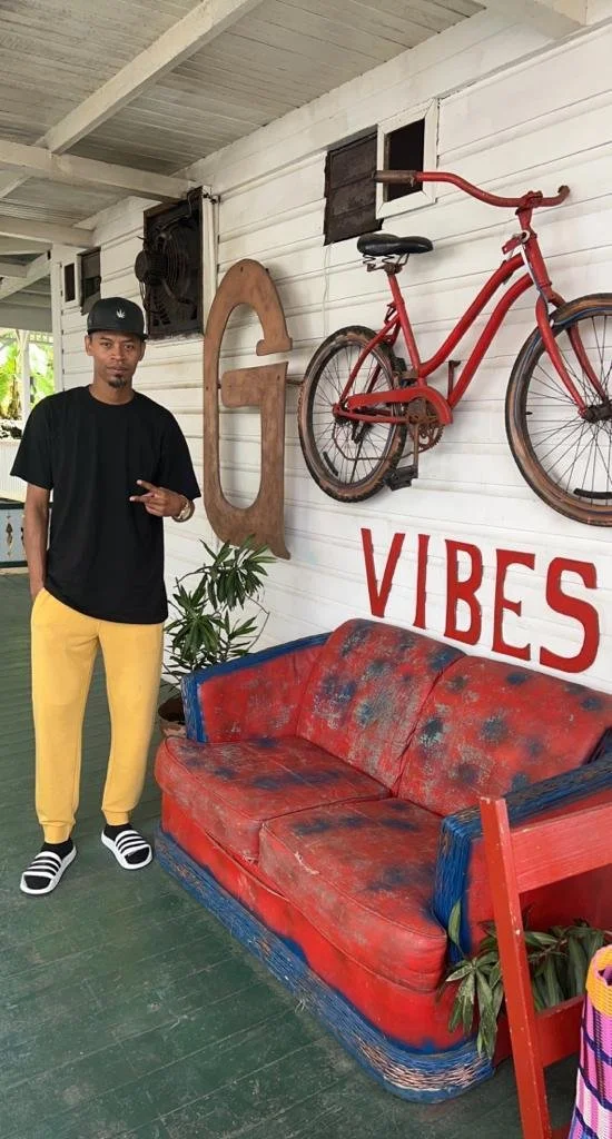 Edgart standing by a red vintage sofa on a porch