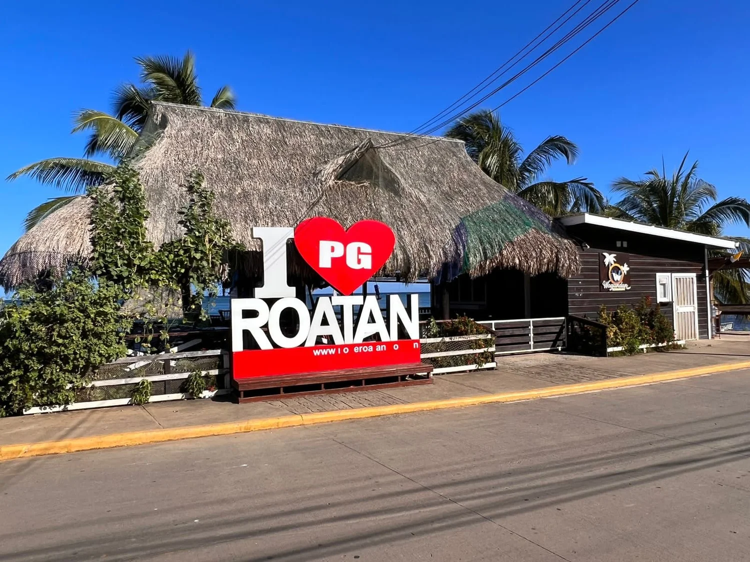 A thatched-roof restaurant with an 'I love Roatan' sign on the East End