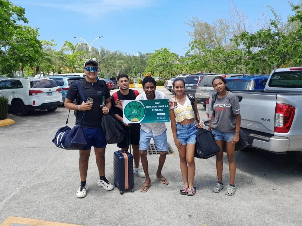 A smiling group holding a Z&Z Roatan Tours sign