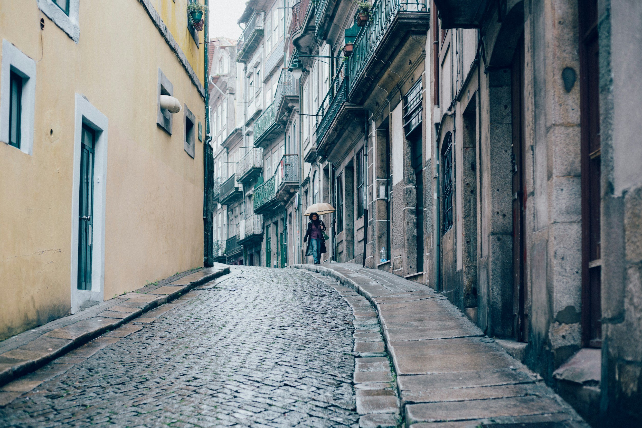 Rain on a cobbled street lined with traditional buildings in Porto
