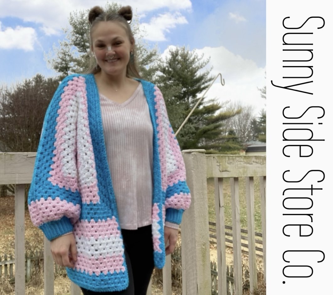 Person wearing a colorful crochet cardigan outdoors with "Sunny Side Store Co." text on side.