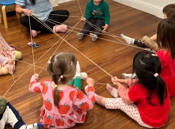 In this photo we have Teacher LayLay from the Garden Class facilitating an activity where each child had shared something that they learned about spiders. After sharing something that they had learned, they would then pass the roll of string to anoth