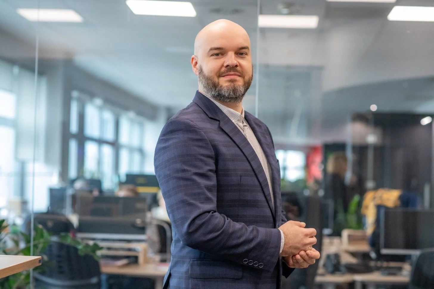 Maciej Boryń w nowoczesnym biurze ze stanowiskami komputerowymi. Ekspert ds. ESG i ładu korporacyjnego, doradzający firmom w zakresie strategii odpowiedzialnego biznesu oraz wymogów dyrektywy CSRD.