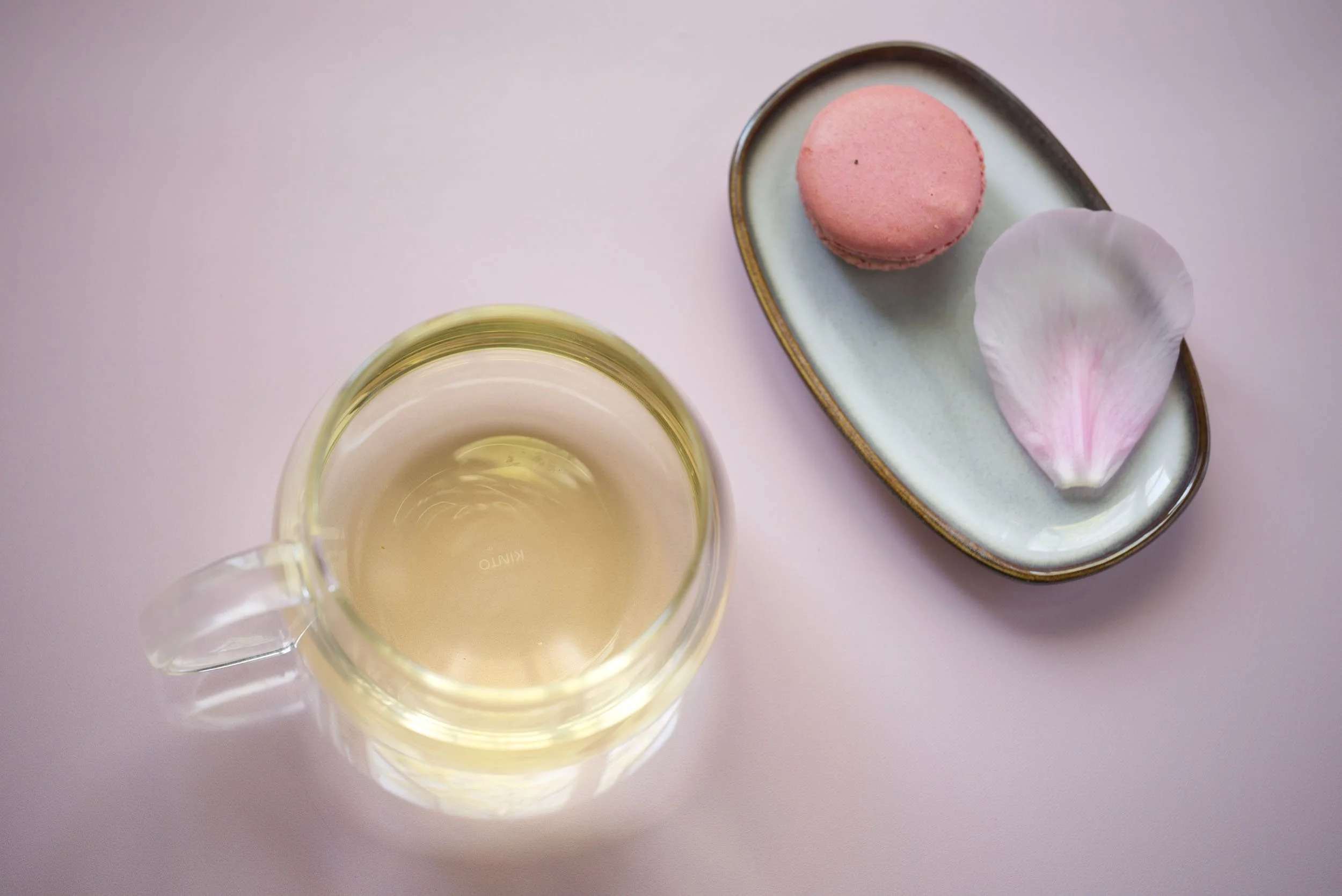 Glass med te og en rosa macaron på en oval skål