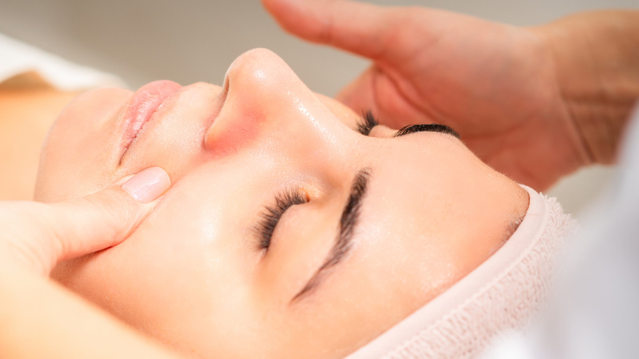 Frau erhält eine Gesichtsmassage in einem Spa, geschlossene Augen, entspannt, weiches Licht