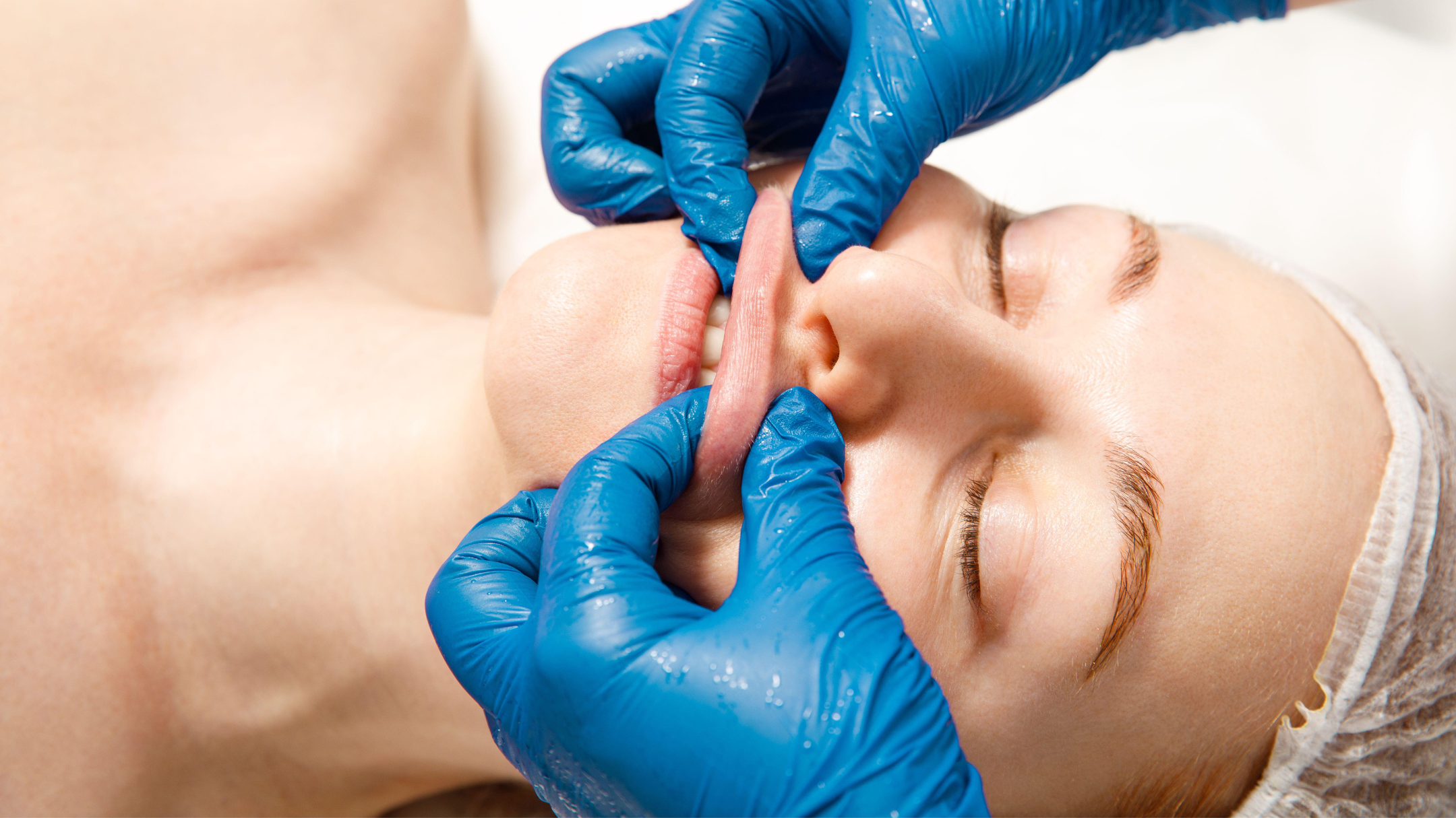 Eine Frau erhält eine Lippenpflegebehandlung in einem Kosmetiksalon, mit blauen Handschuhen des Kosmetikers.