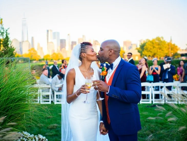 First kiss at Liberty State Park wedding ceremony with guests celebrating