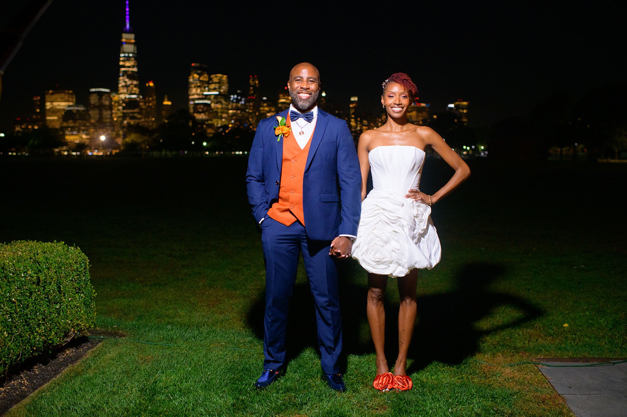Couple holding hands at Liberty State Park outside at night with city view