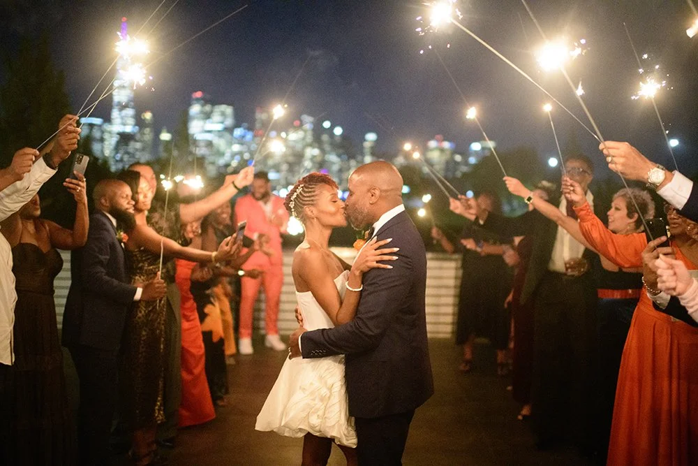 Romantic kiss photo at Liberty State Park wedding outside with sparklers and city backdrop