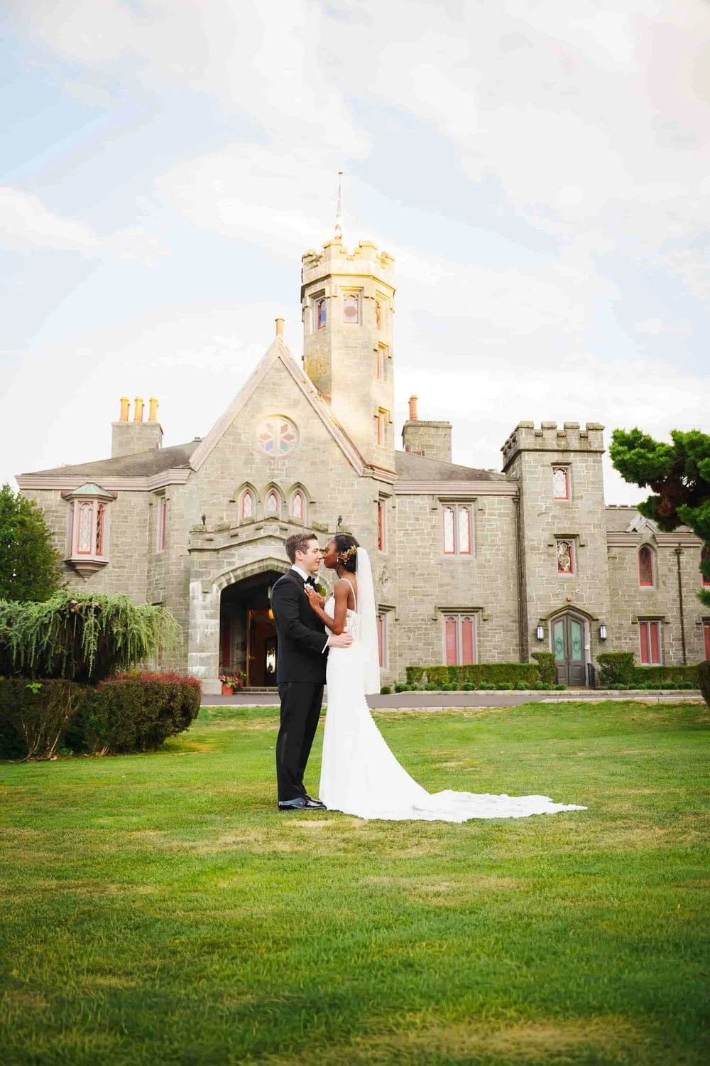 Bride and groom standing close together in front of Whitby Castle