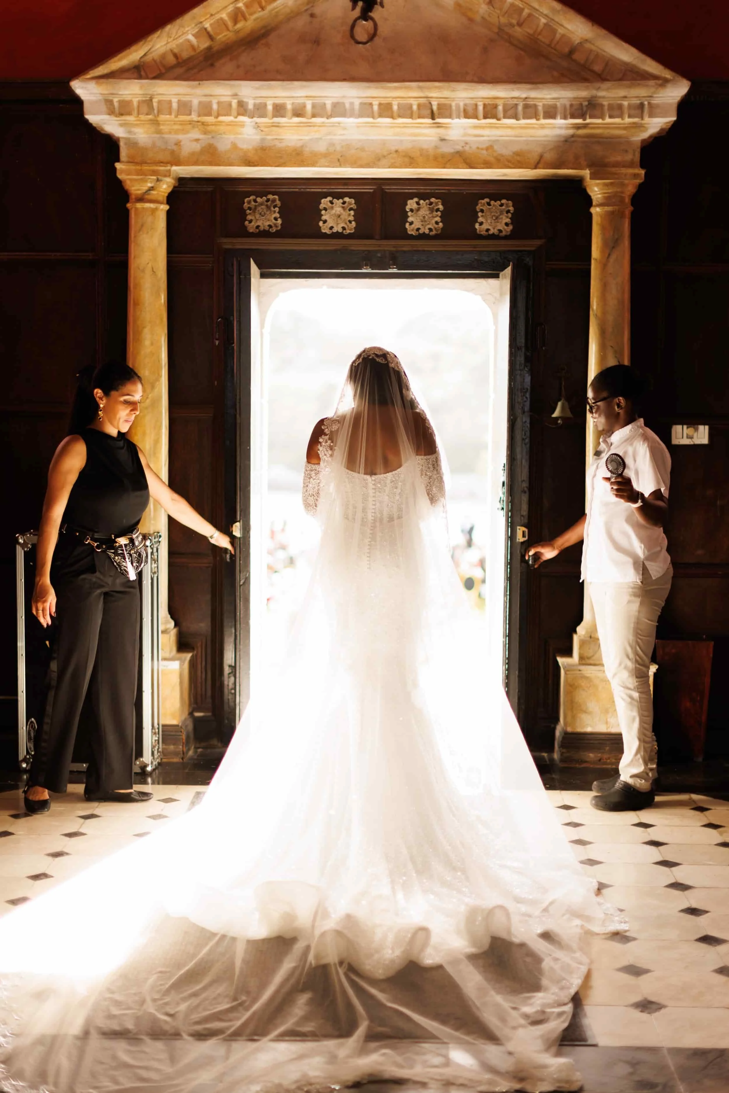 Bride entering ceremony during Trident Castle wedding with dramatic backlit doorway moment in Jamaica