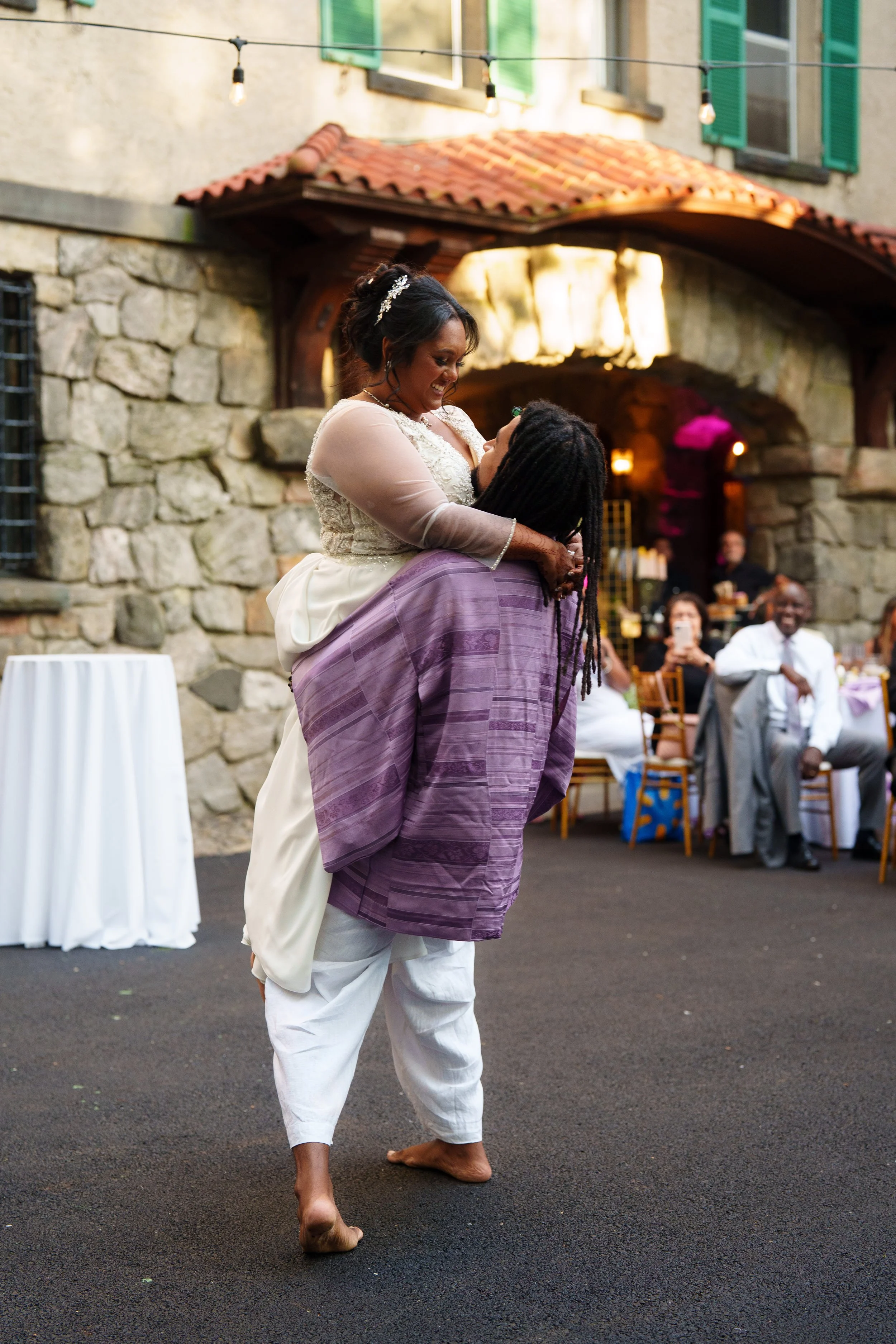Groom lifting bride during first dance at outdoor Arrow Park wedding reception Monroe NY with string lights