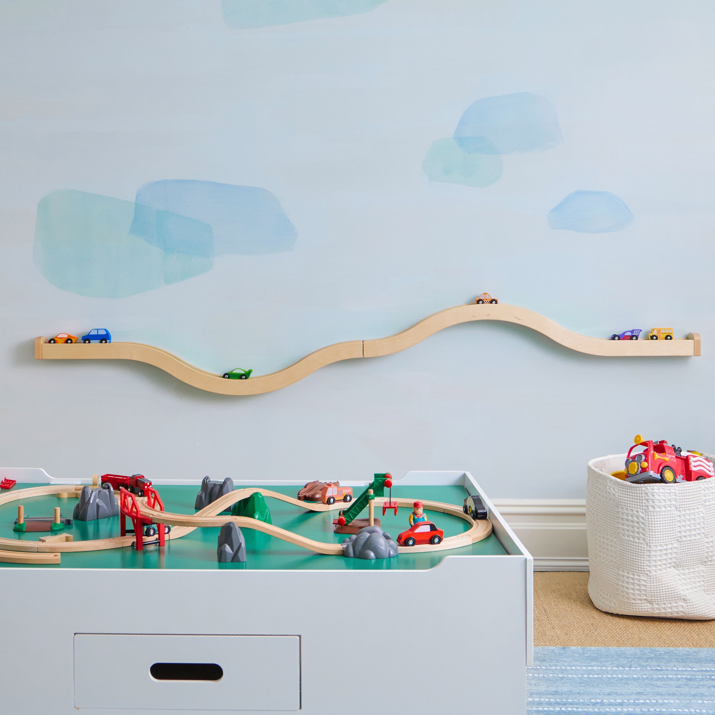 Kids' train table with wall mounted train and car track in background 