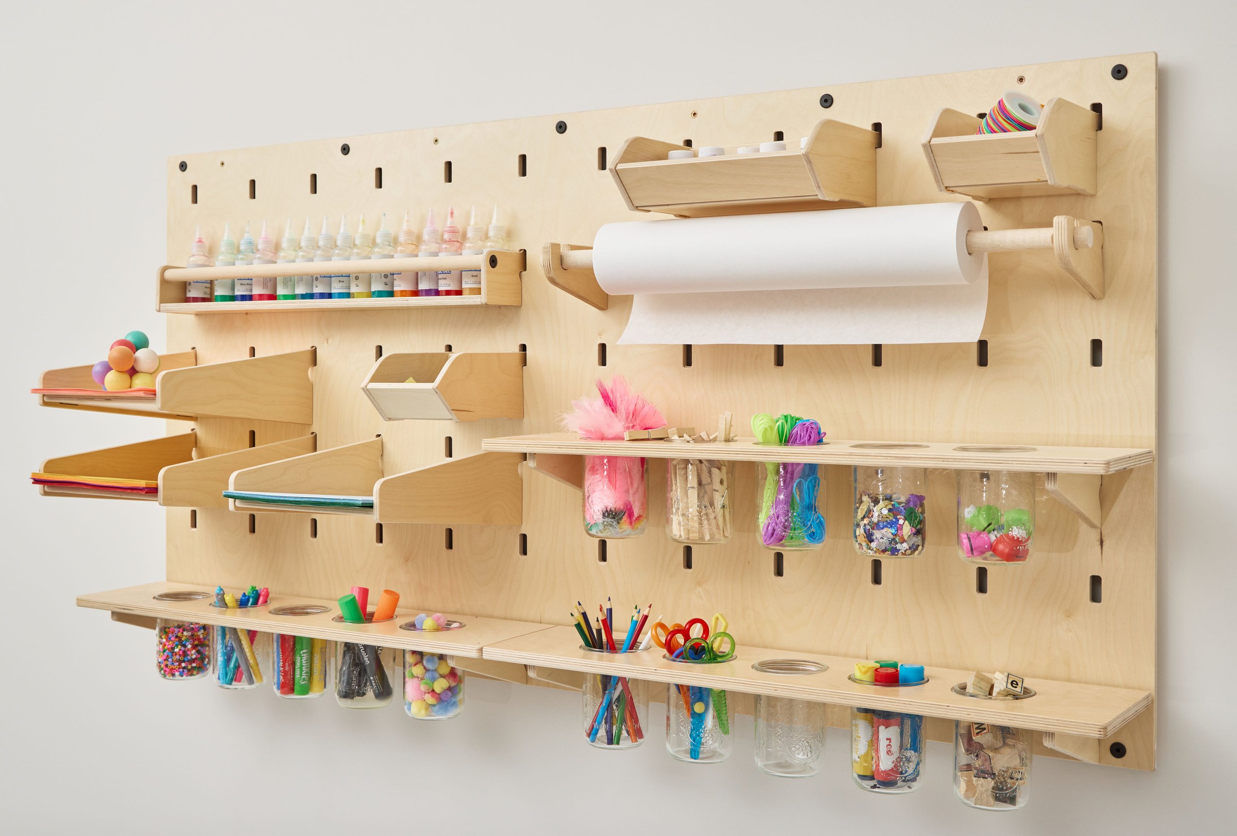 Wall-mounted kids' art supply organizer with pegboard, bins, paper roll and clear storage jars