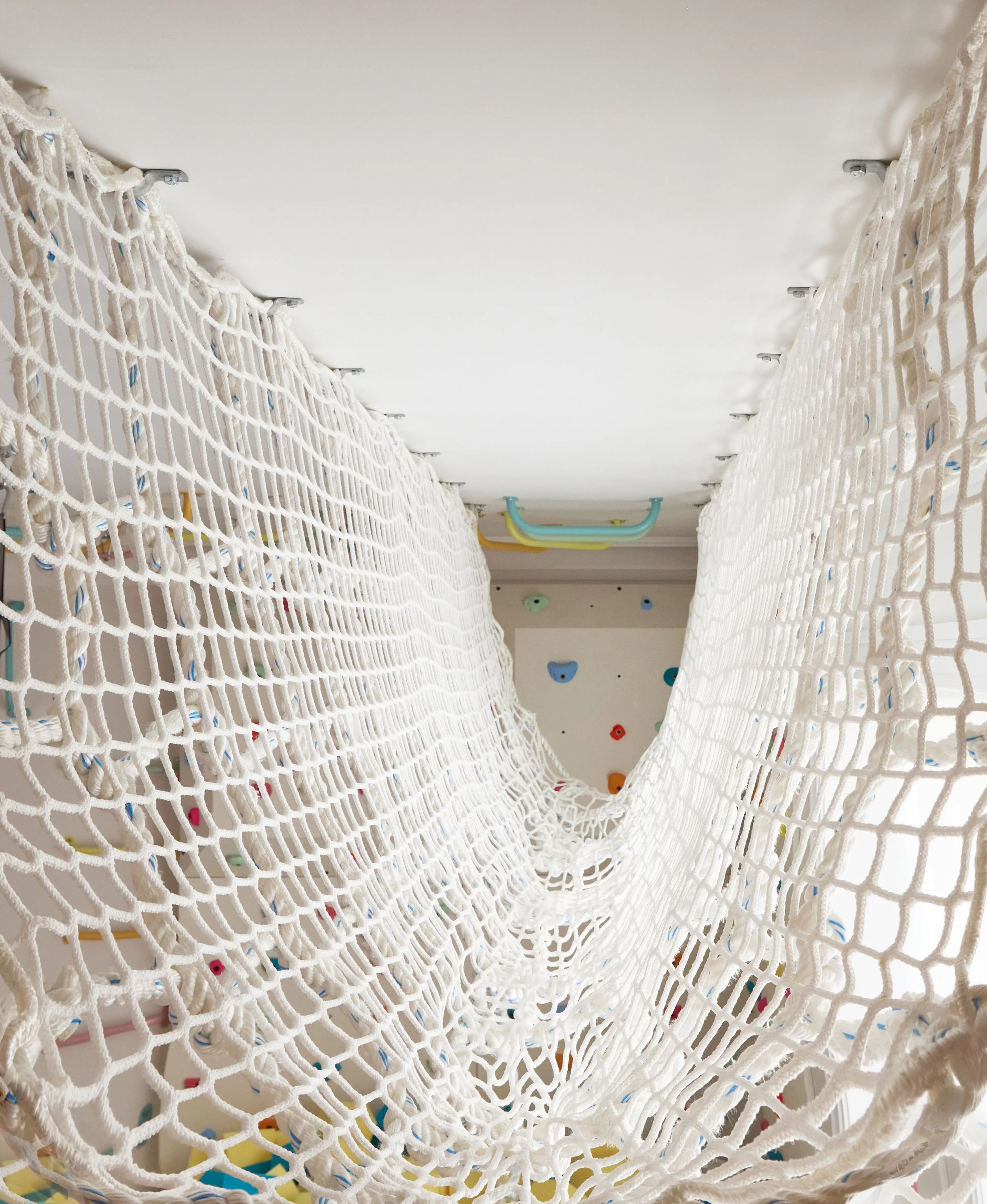 View through rope tunnel hung from ceiling in kids playroom
