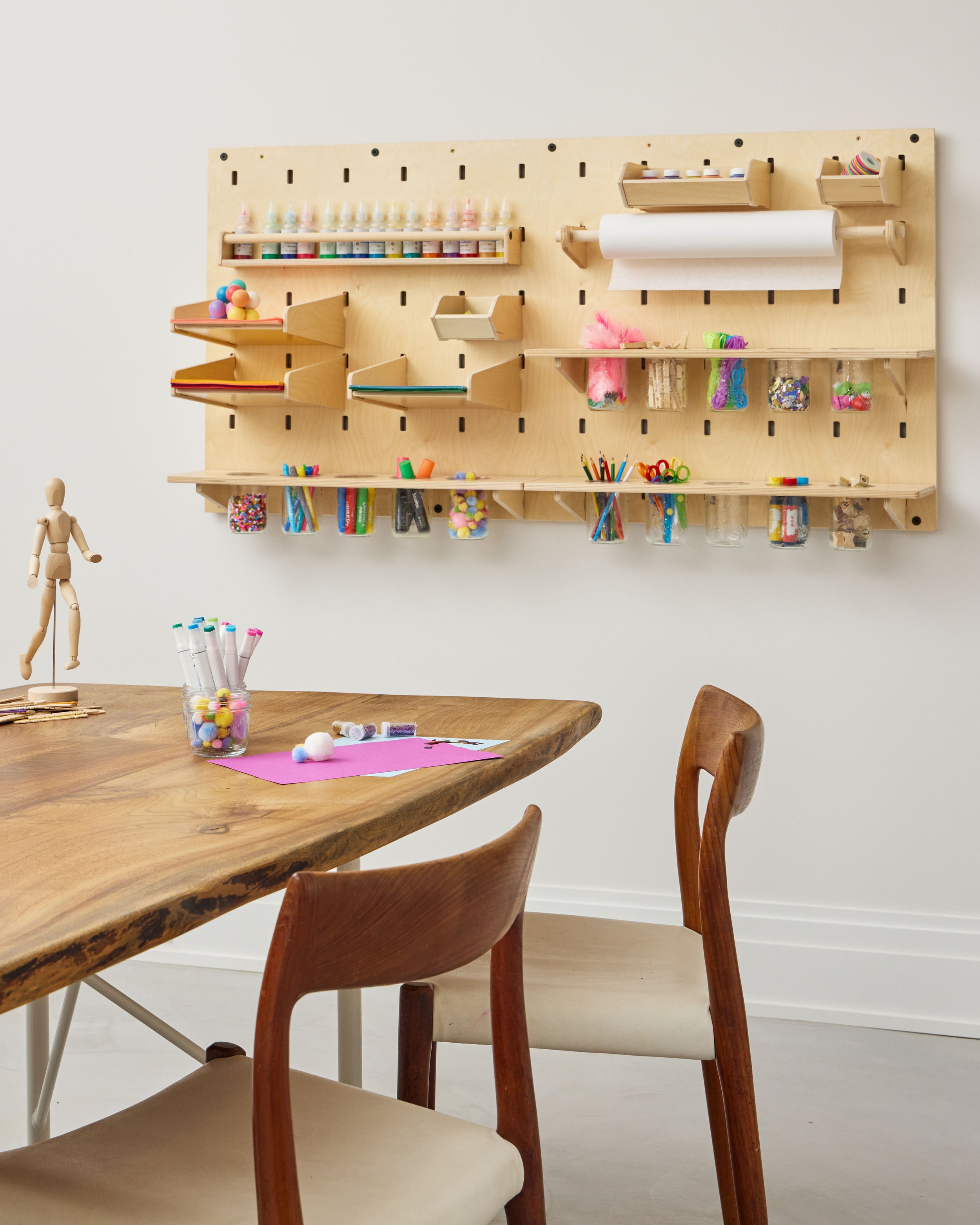 table and chairs in foreground with wall mounted kids' arts and crafts pegboard storage in background