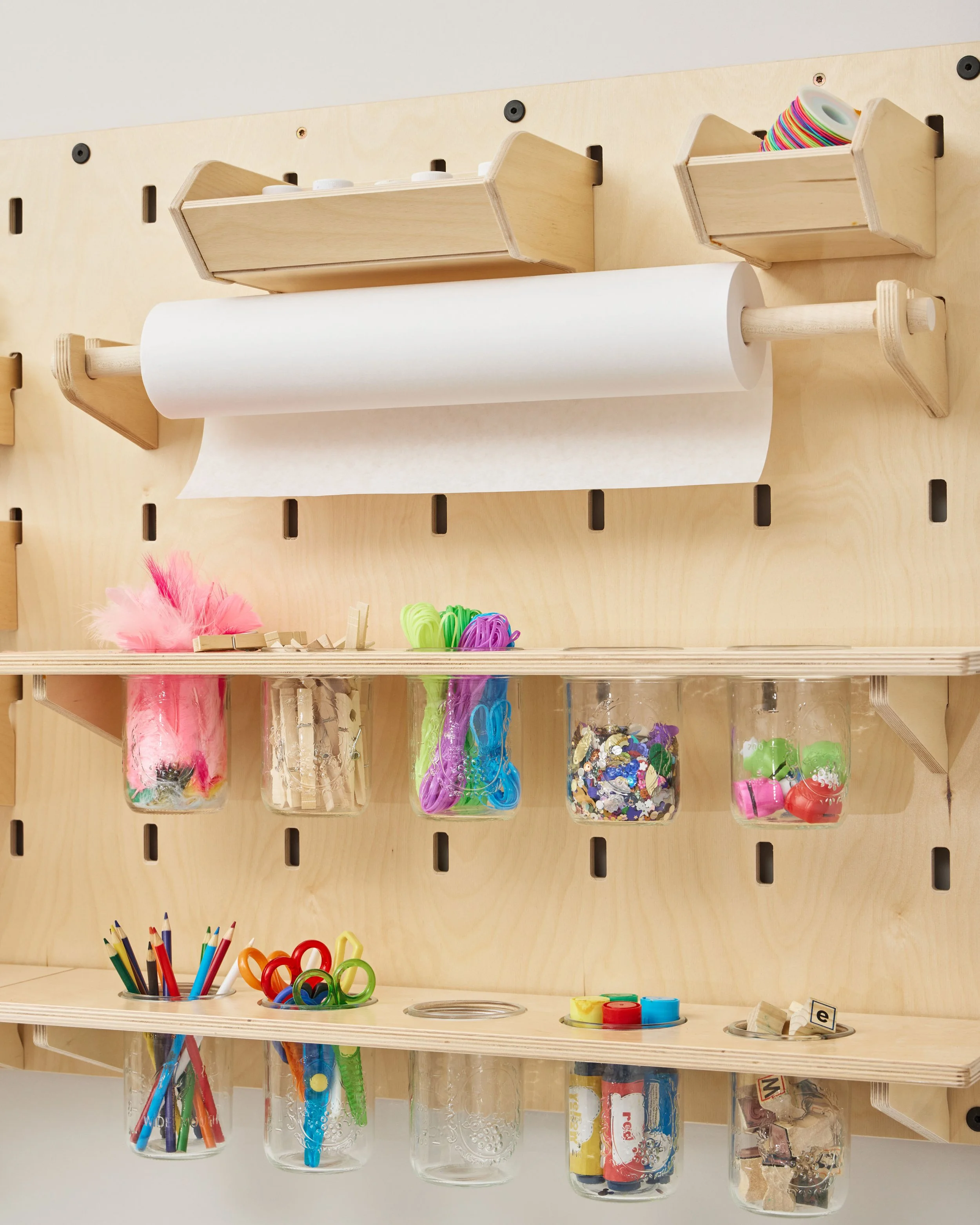 Kids' arts and crafts storage with paper roll and clear jars of colorful craft supplies