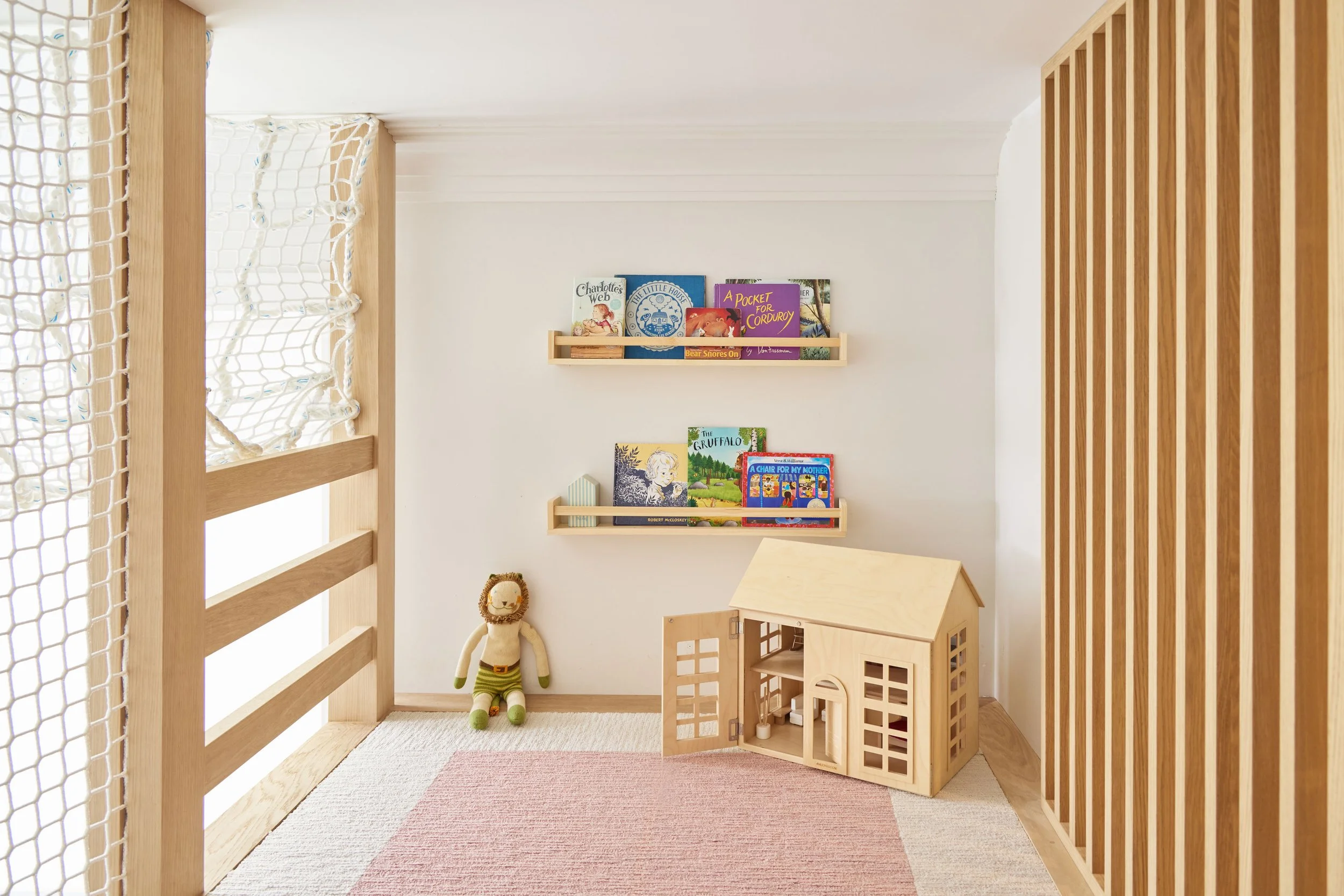Upper-level kids' play fort with forward-facing bookshelves, playhouse and safety netting