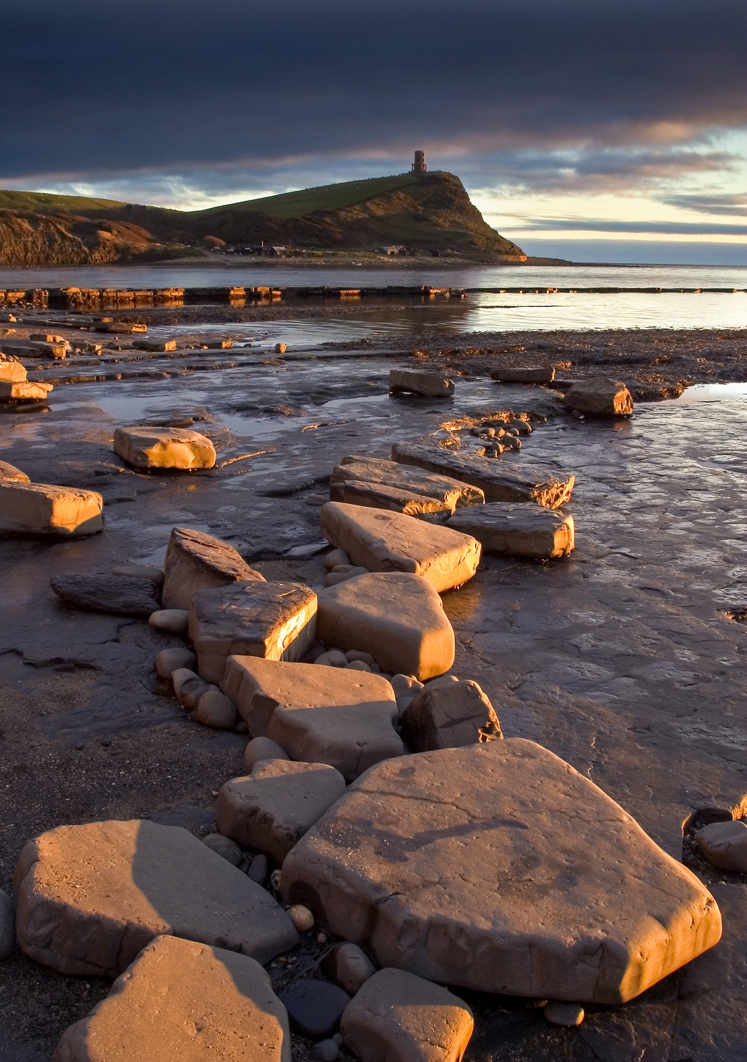 End of the Day, Kimmeridge - Sunset at Kimmerdige Bay with the Clavell Tower standing proud on the cliffs beyond and the rocks in the foreground catching the last light of the setting sun.