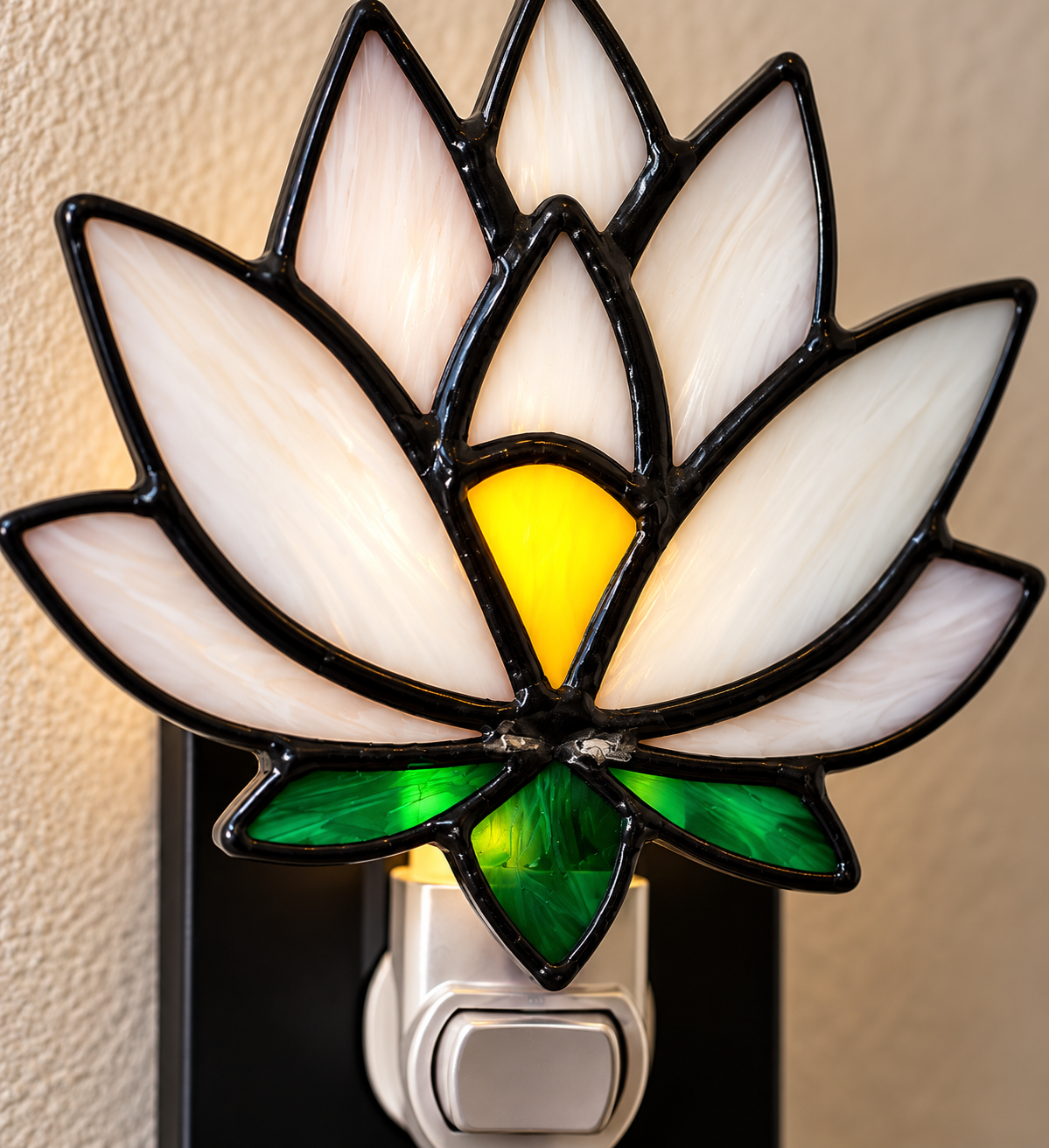 Close-up of handmade lotus stained glass night light showing white glass petals and green leaves