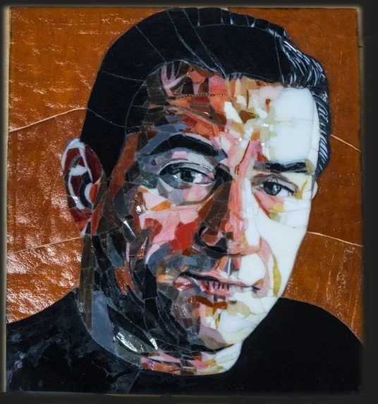 Close-up of a collage portrait of a man with glasses, dark hair, and a bright expression against a brown background.