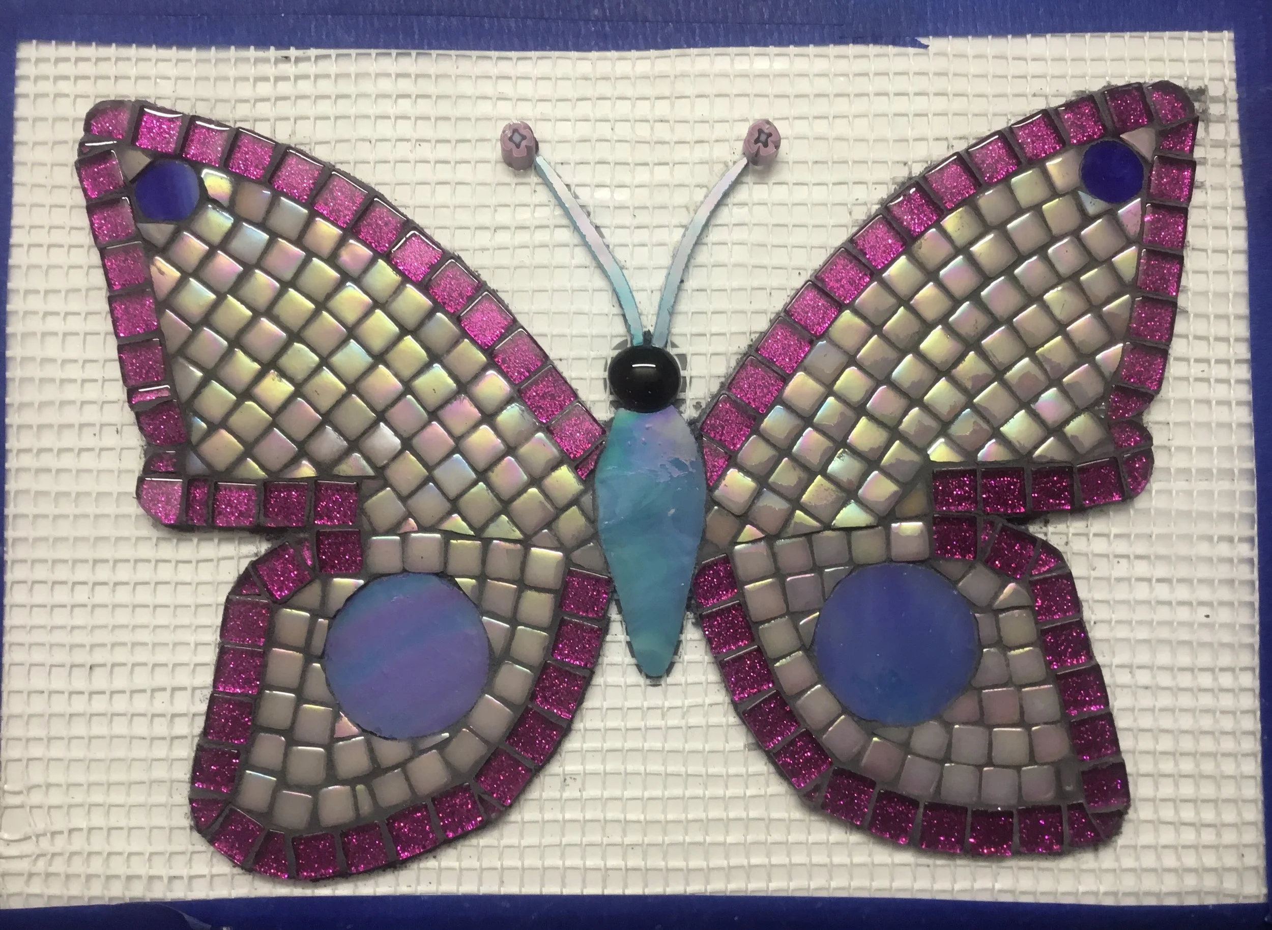 Mosaic butterfly artwork with pink and purple border, set against a white textured background.