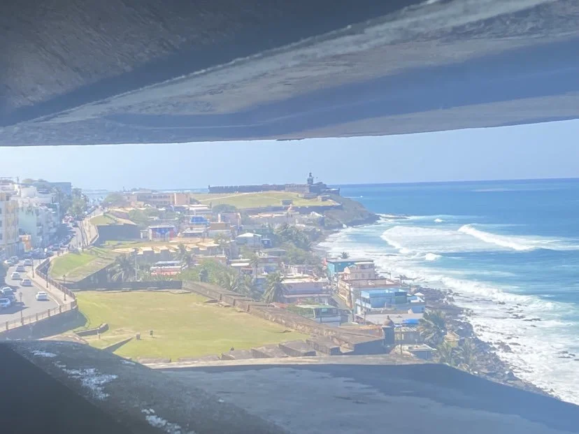 View of coastal city and ocean seen through an opening in a structure.