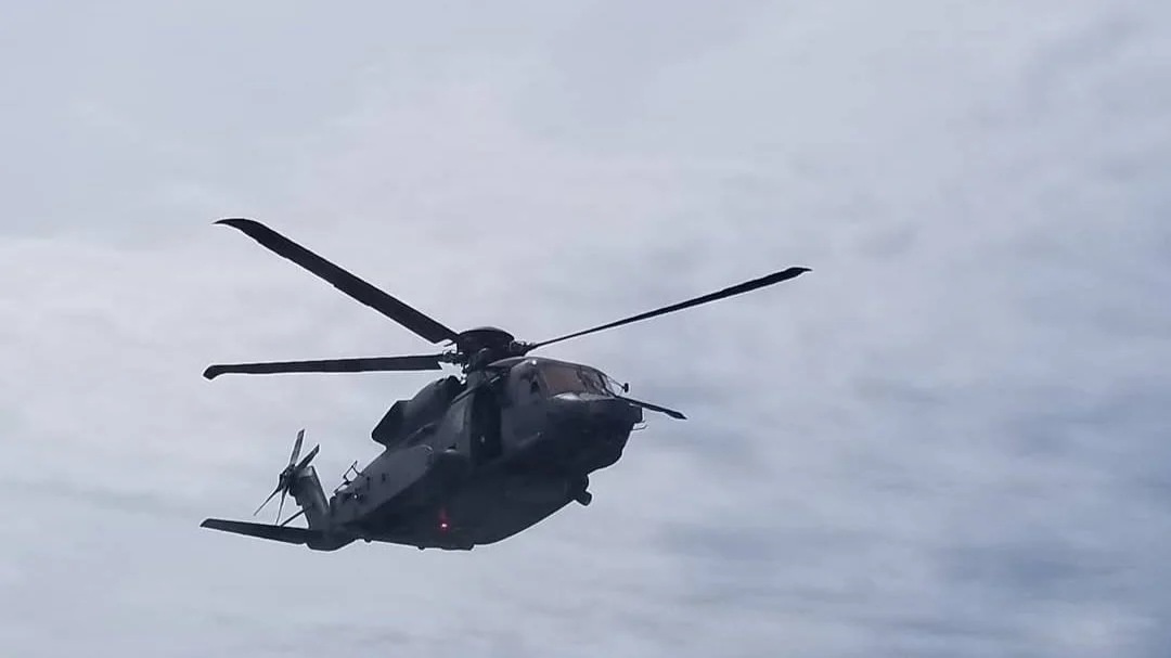 Black military helicopter flying in cloudy sky
