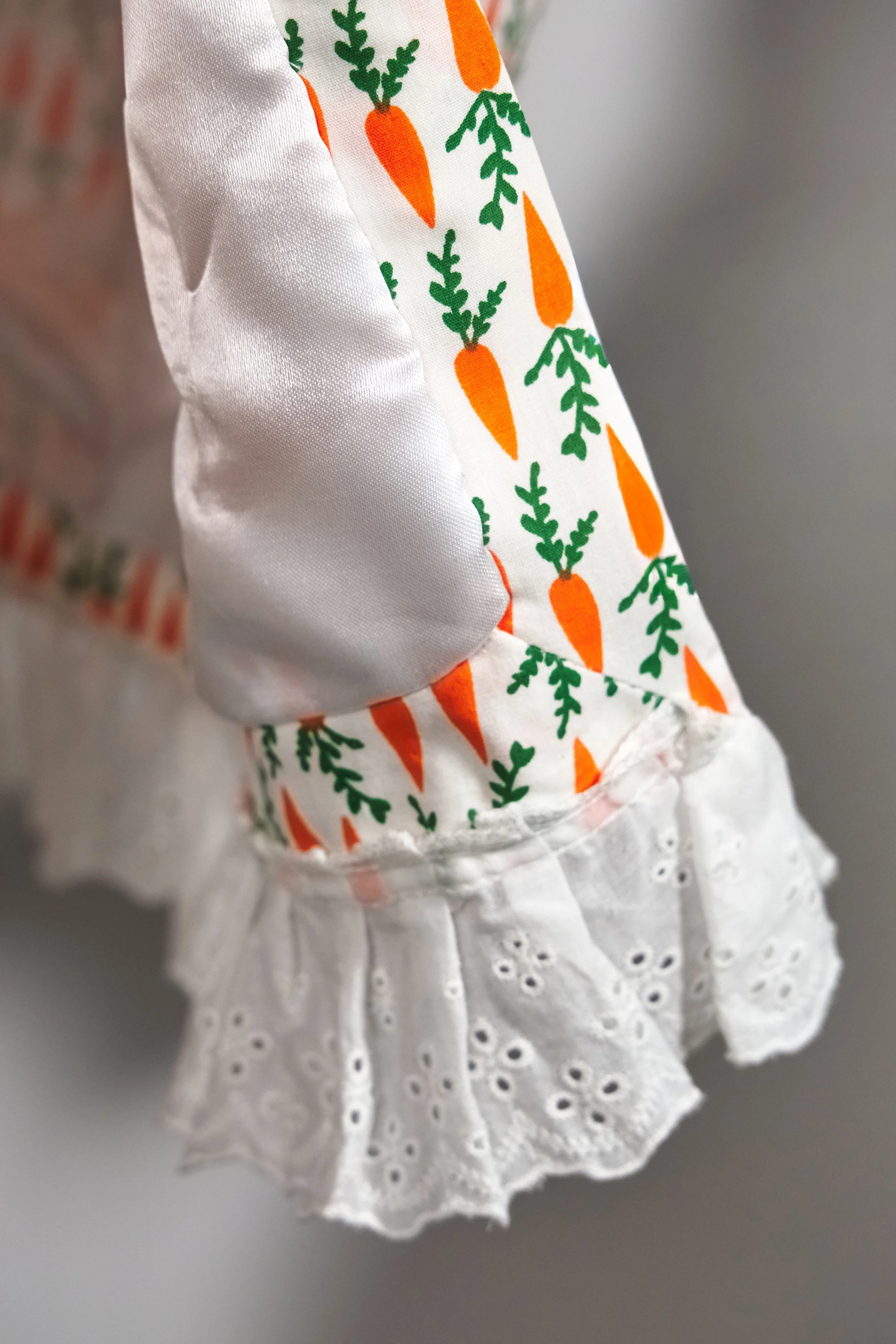 Close-up of carrot print cotton fabric and white eyelet lace hem detail — Carrot Cake by B.Brand