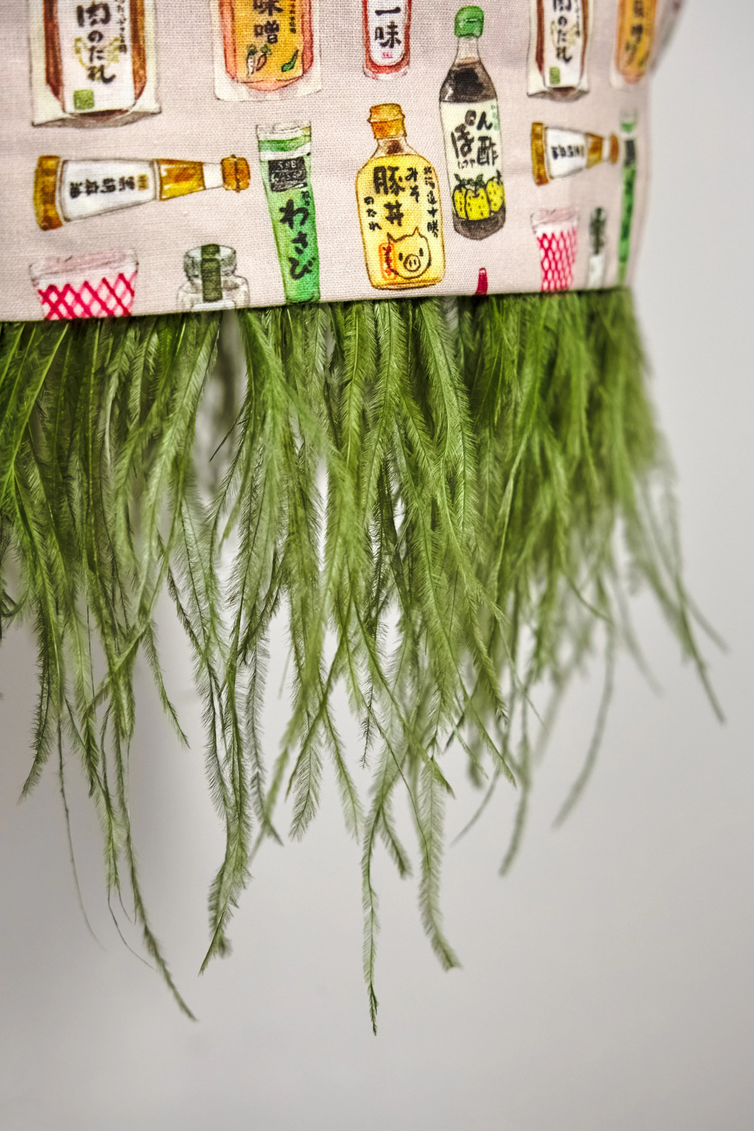 Detail of wasabi-green feather attachment and button seam on cream condiment print skirt — Wasabi Lover by B.Brand