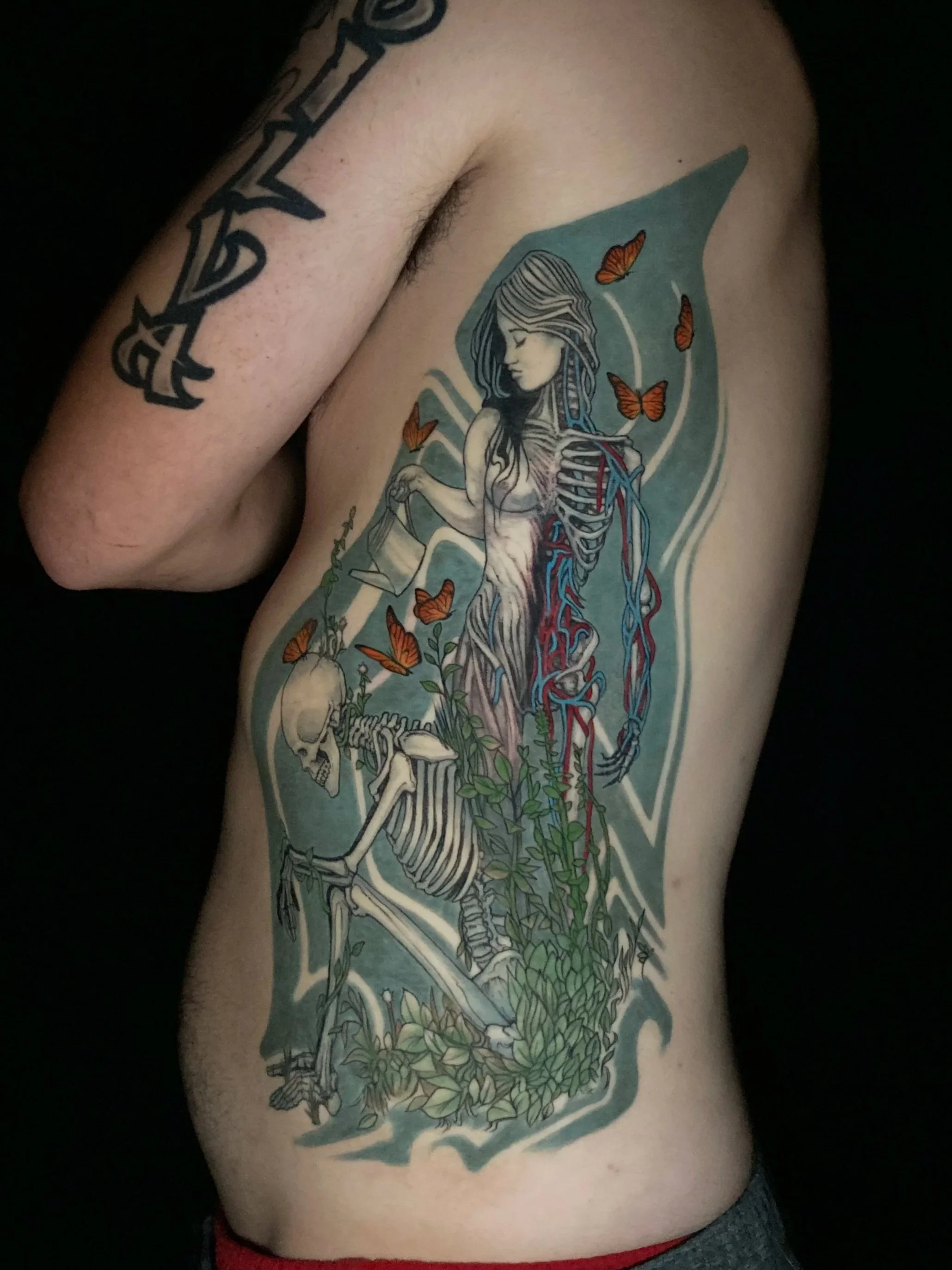 colorful tattoo large rib piece woman with skeleton in garden watering flowers growing with butterflies abstract background