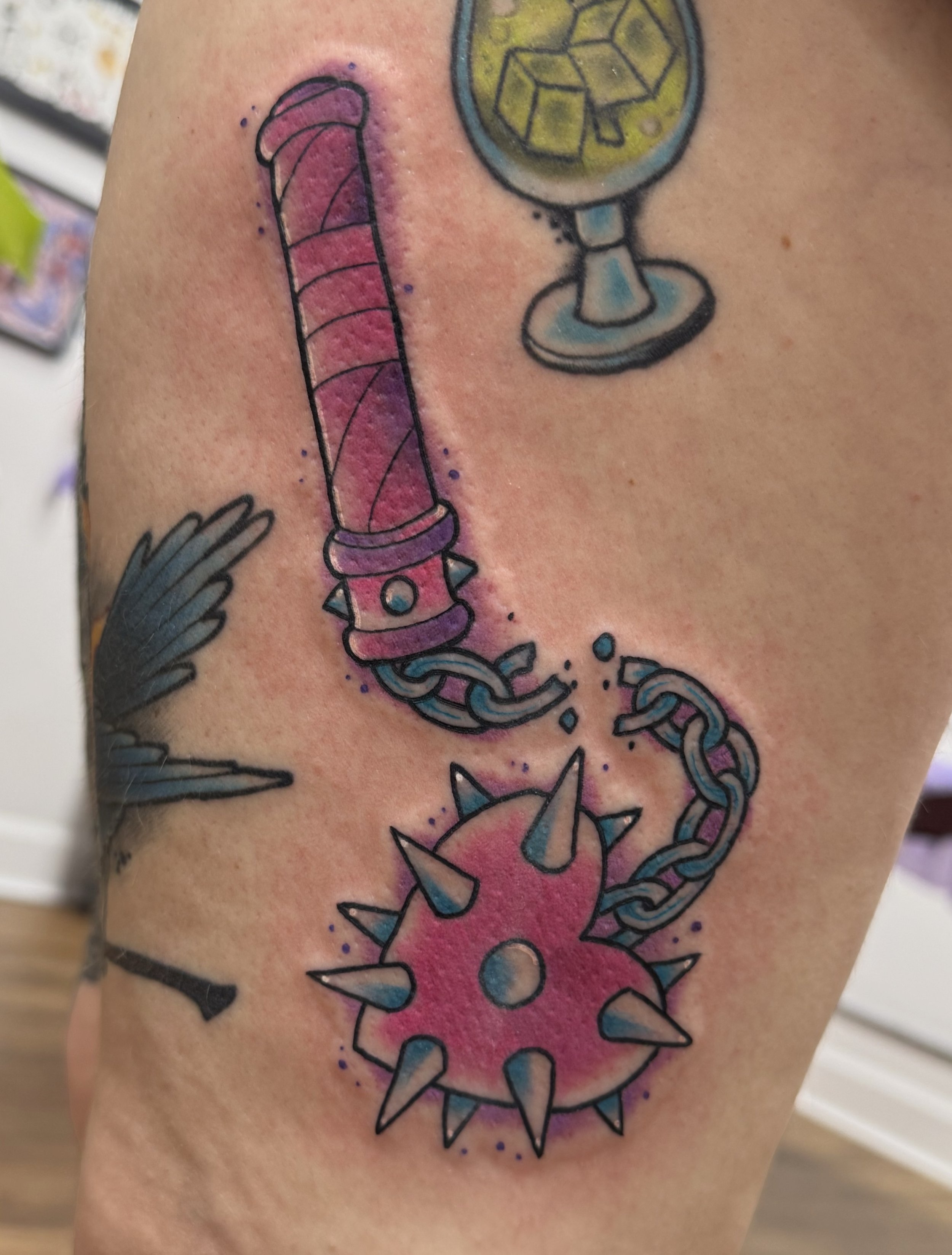 Tattoo of a Halloween-themed Jack-o'-lantern with a smiling face, surrounded by green leaves, and decorated with string beads hanging from the top. Chelsea Graham illustrative, american traditional, and kawaii tattoo artist seattle washington.