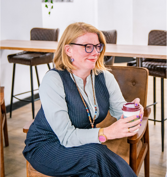 Tineke Zoet, maritime workplace consultant, in a grey suit holding a cup of tea