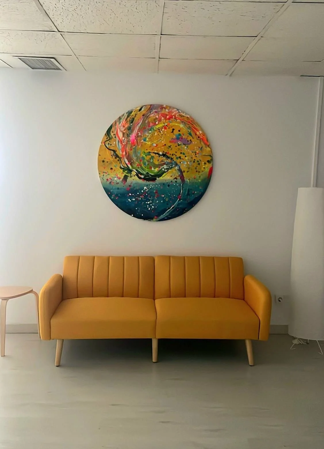 Sala de bienestar con Sofá amarillo en un salón con pintura abstracta en la pared
