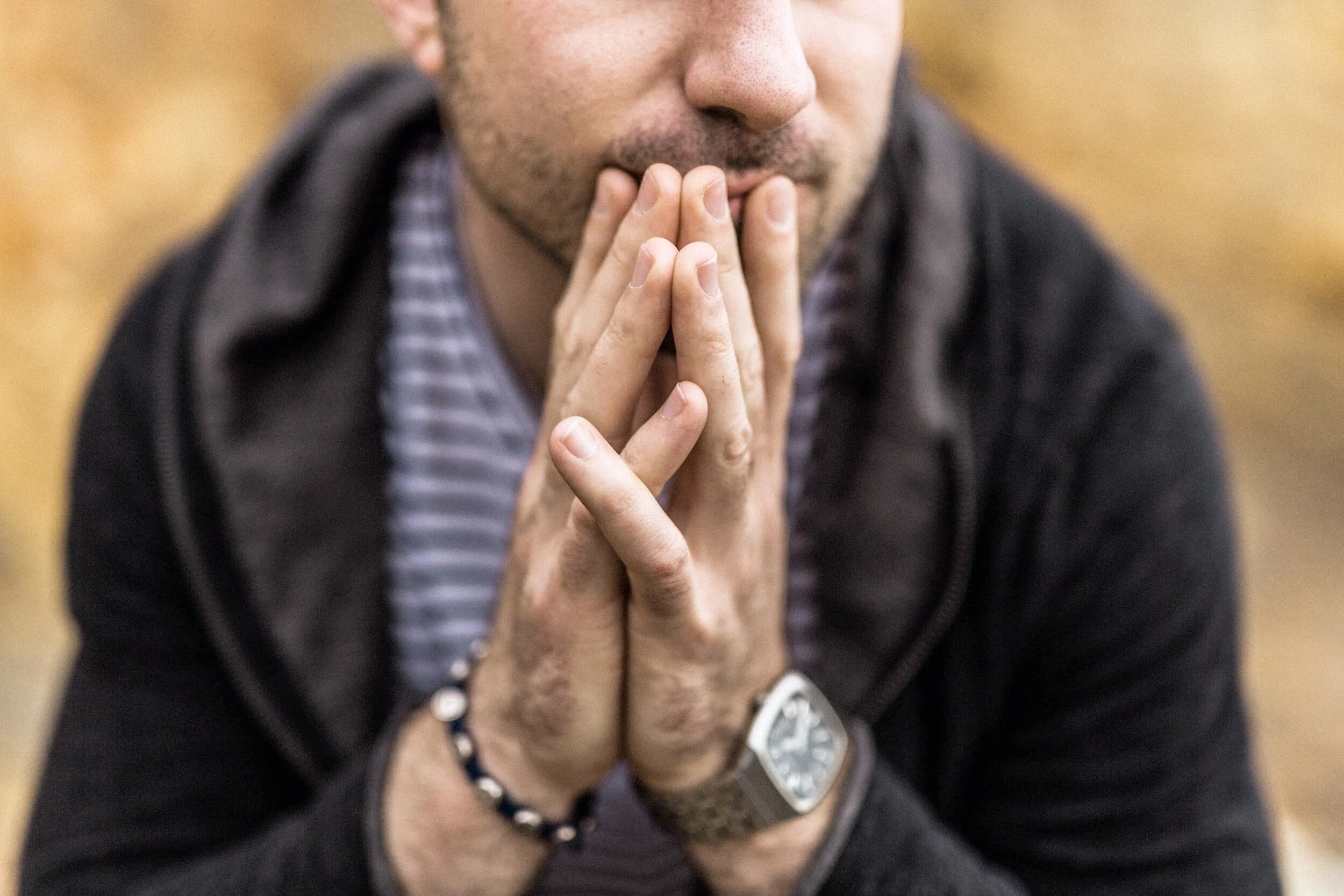 man clasping hands in front of chin
