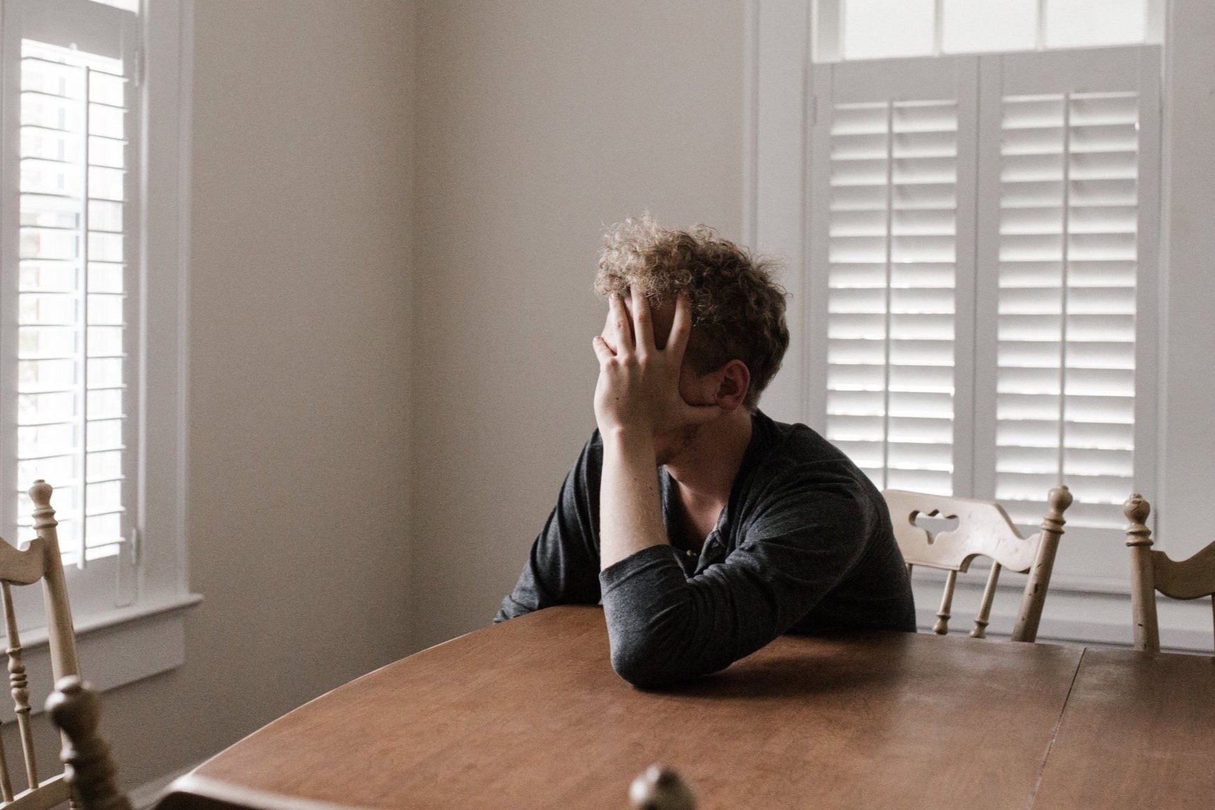 man sitting at table resting head on hand