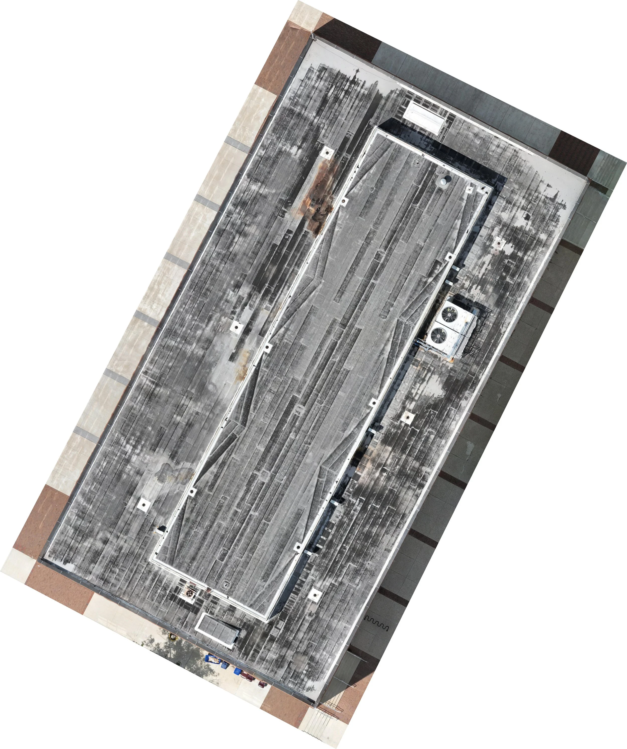 An aerial view of a multi-story parking garage with cars parked along the edges, a rooftop HVAC system, and a surrounding sidewalk area.