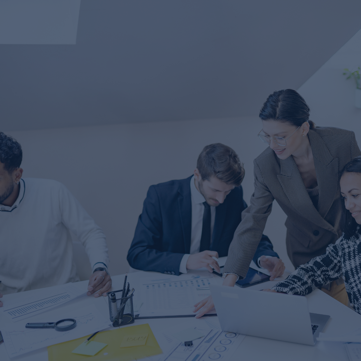 Vier Personen arbeiten an einem Tisch gemeinsam an Auswertungen und Diagrammen. Eine Frau beugt sich zu einer Kollegin und zeigt etwas auf dem Laptop.