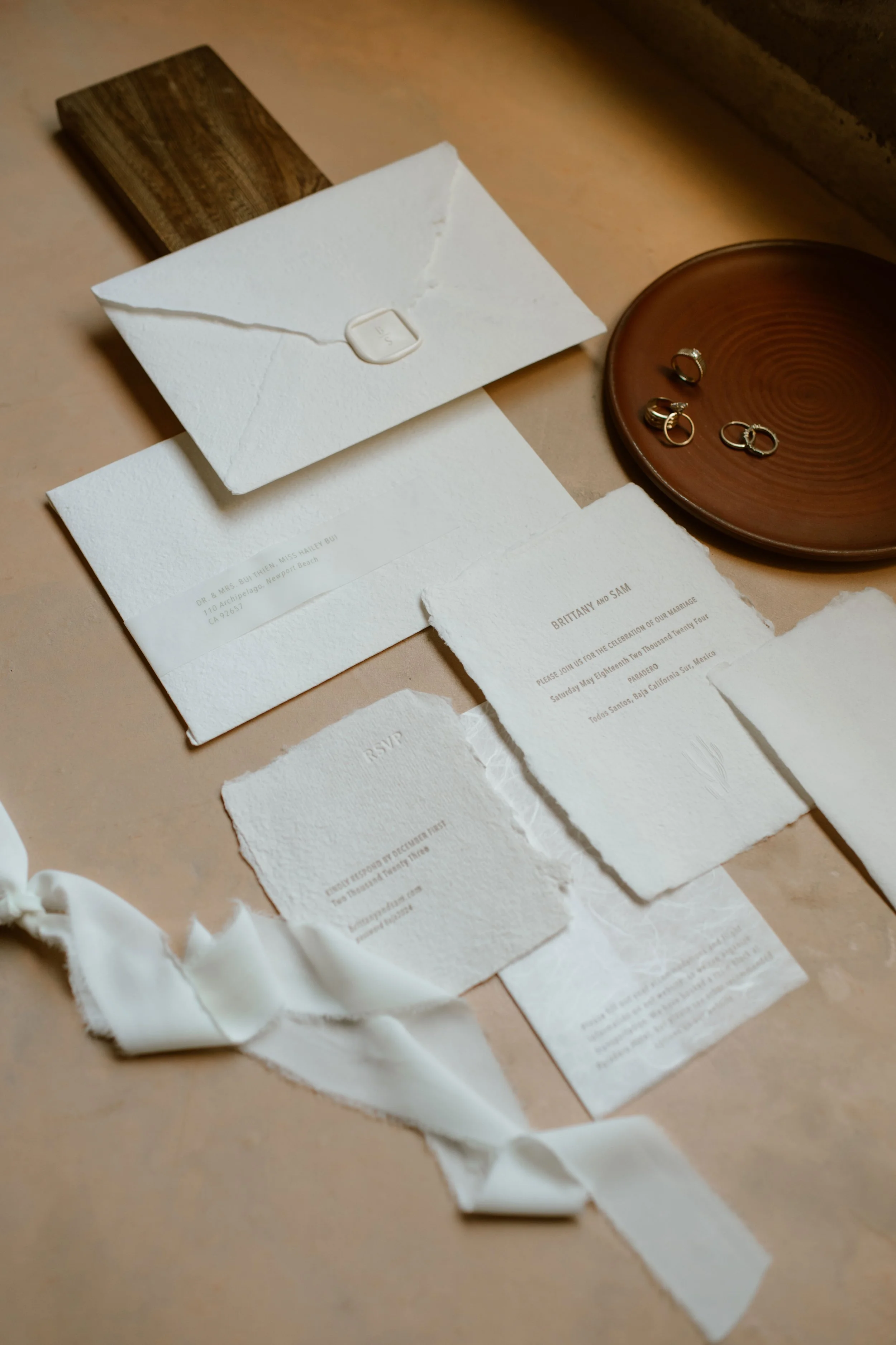 Papier June wedding invitation suite with handmade paper, flat lay with an envelope, and a white fabric ribbon