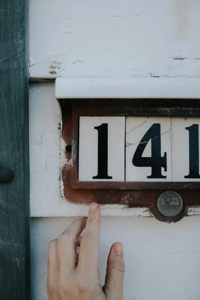 an outstretched hand touching house numbers