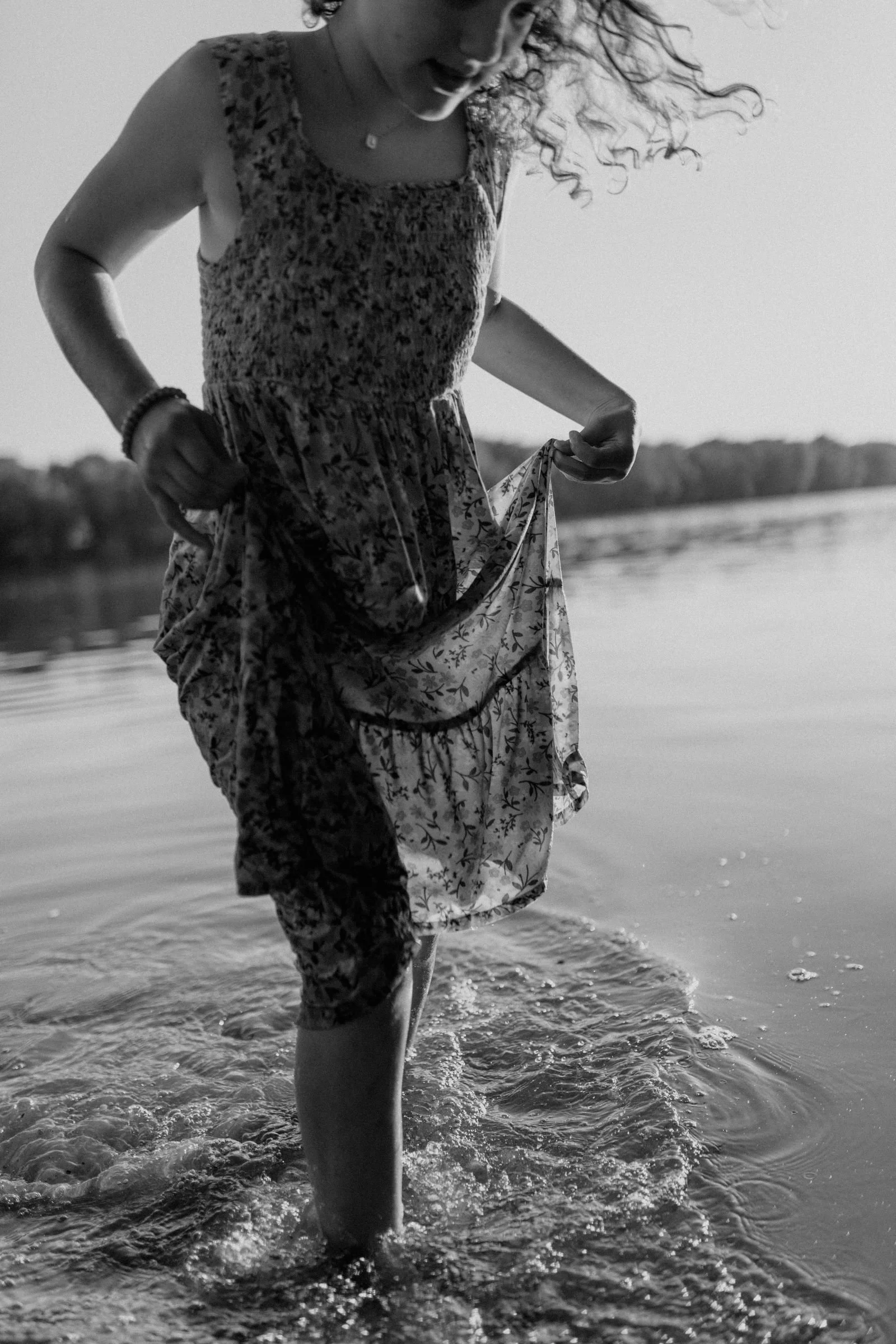 little girl holding up a flowered dress as she runs through the Susquehanna river 