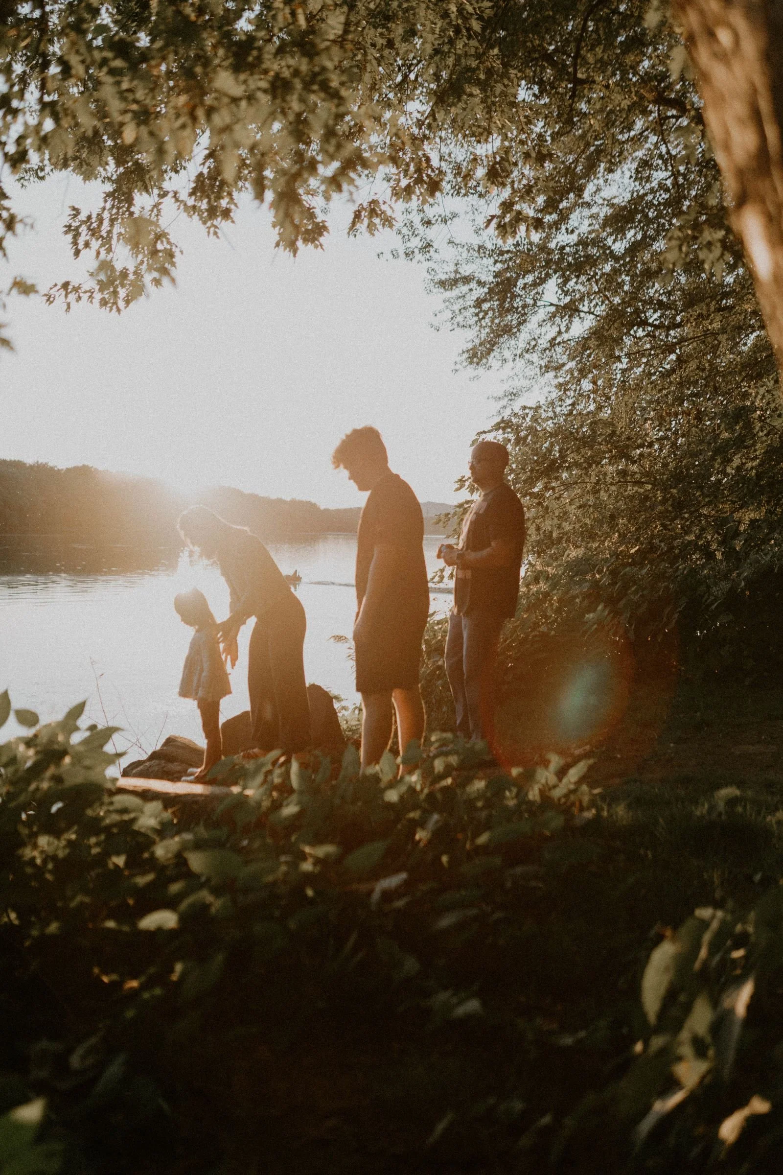 A silhouette of a family of four in the woods by the river at Canfield Island as the sun goes down in Montoursville, Pennsylvania