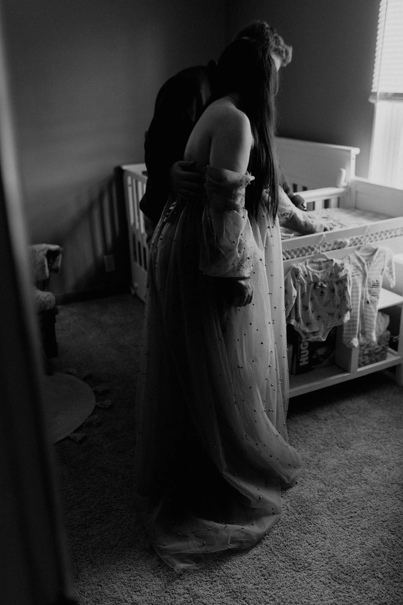 candid black and white photo of parents to be looking at their baby's nursery