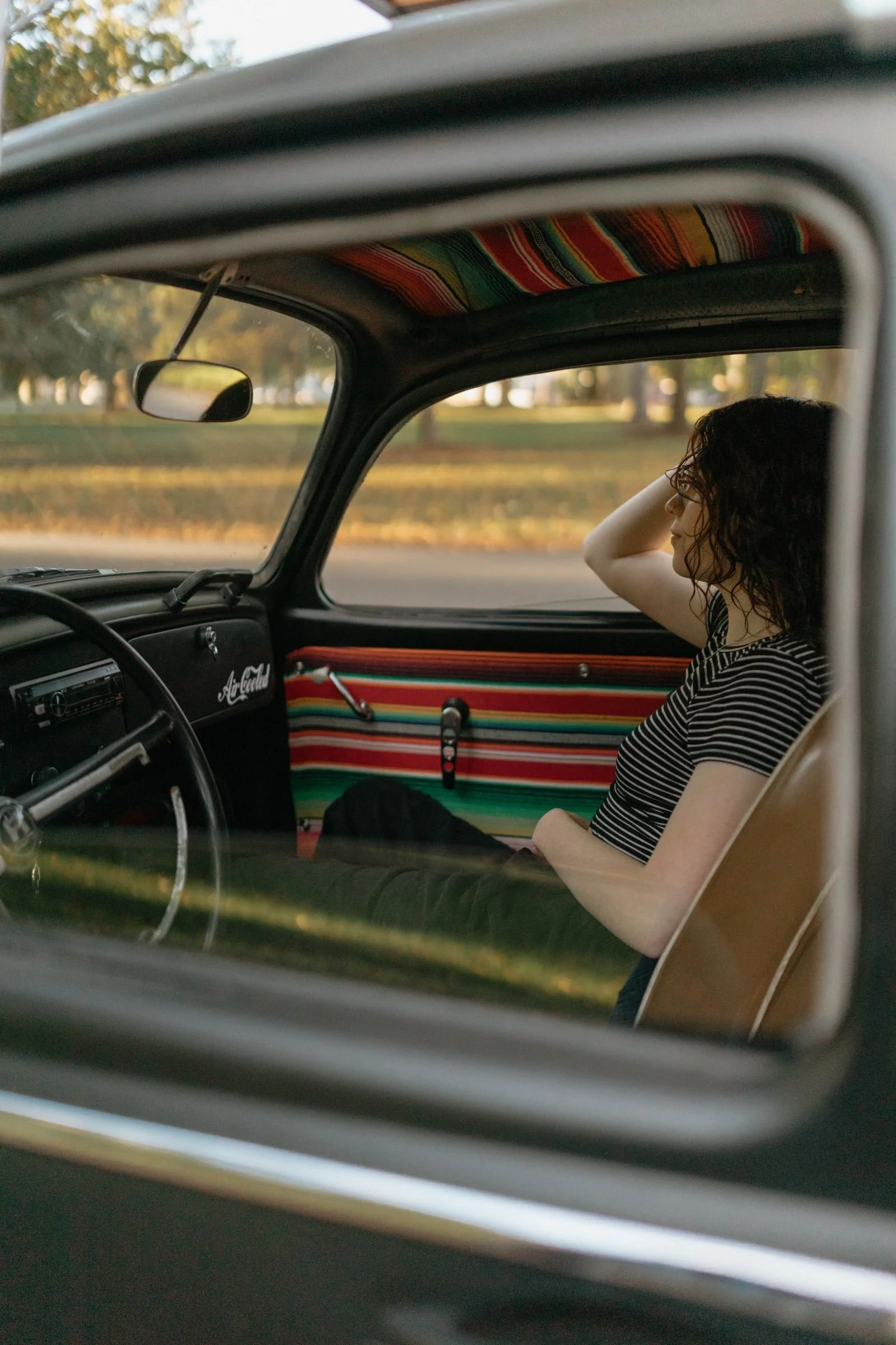 senior picture of a young woman in a black Volkswagen beetle with a rainbow interior